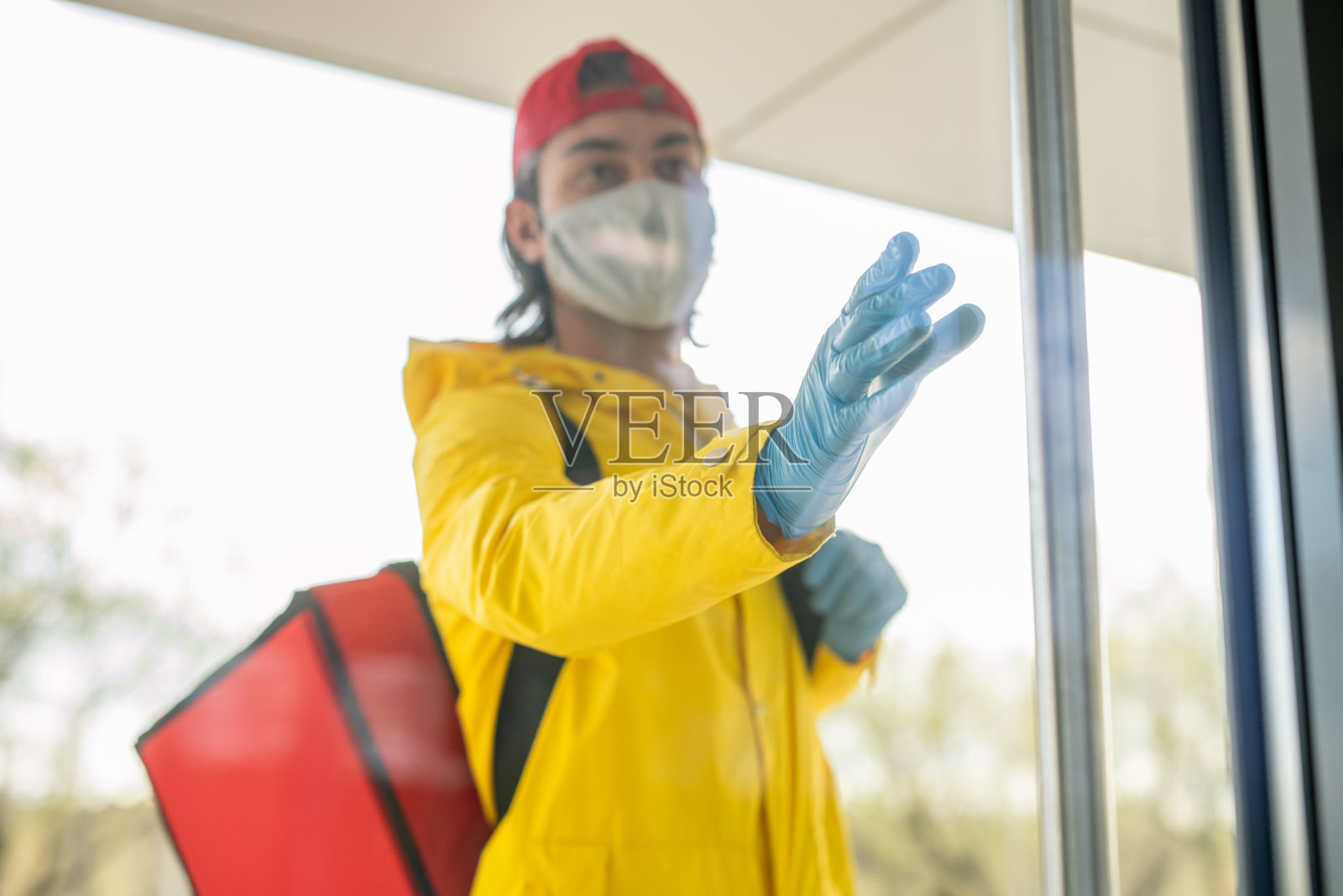 年轻男快递手戴防护面具，黄色工作服和帽子照片摄影图片