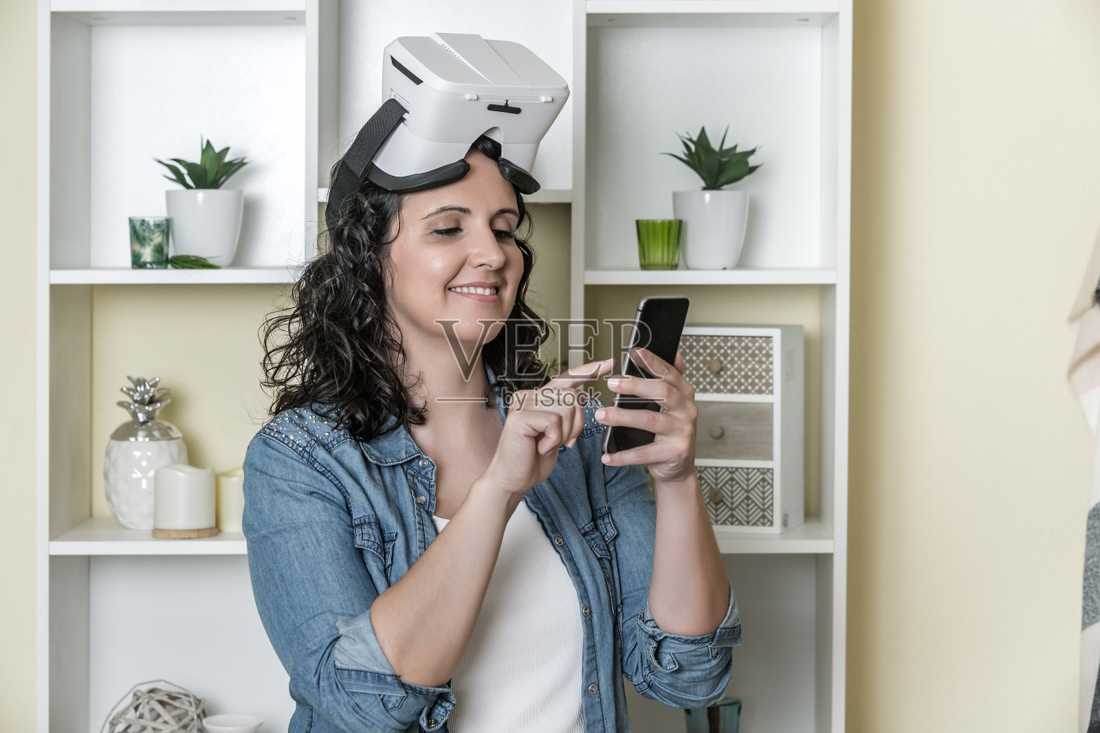 快乐的成年女性戴着虚拟现实眼镜在家使用智能手机照片摄影图片