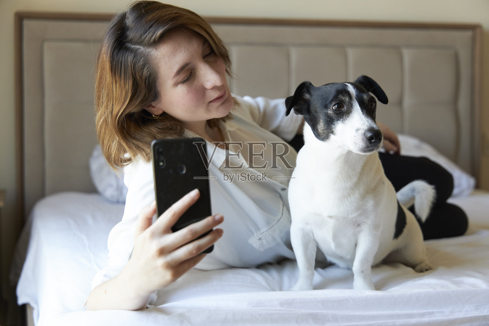 快乐的女人和狗在床上自拍照片摄影图片