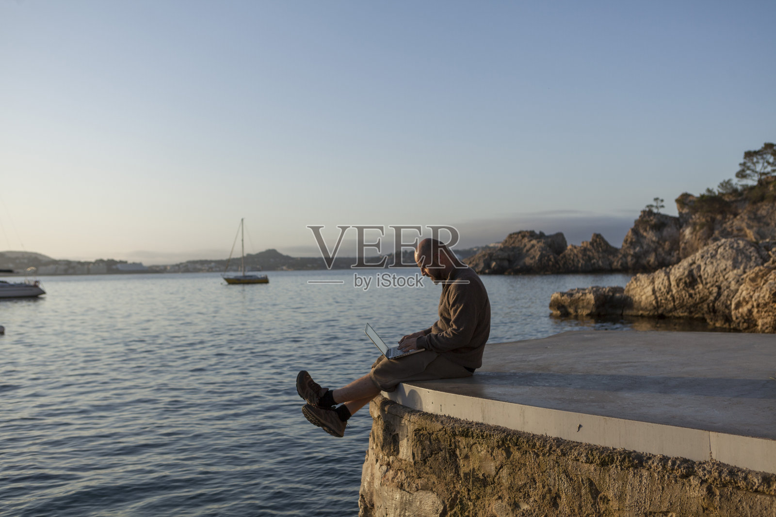 一个年轻人在日出时使用笔记本电脑。照片摄影图片
