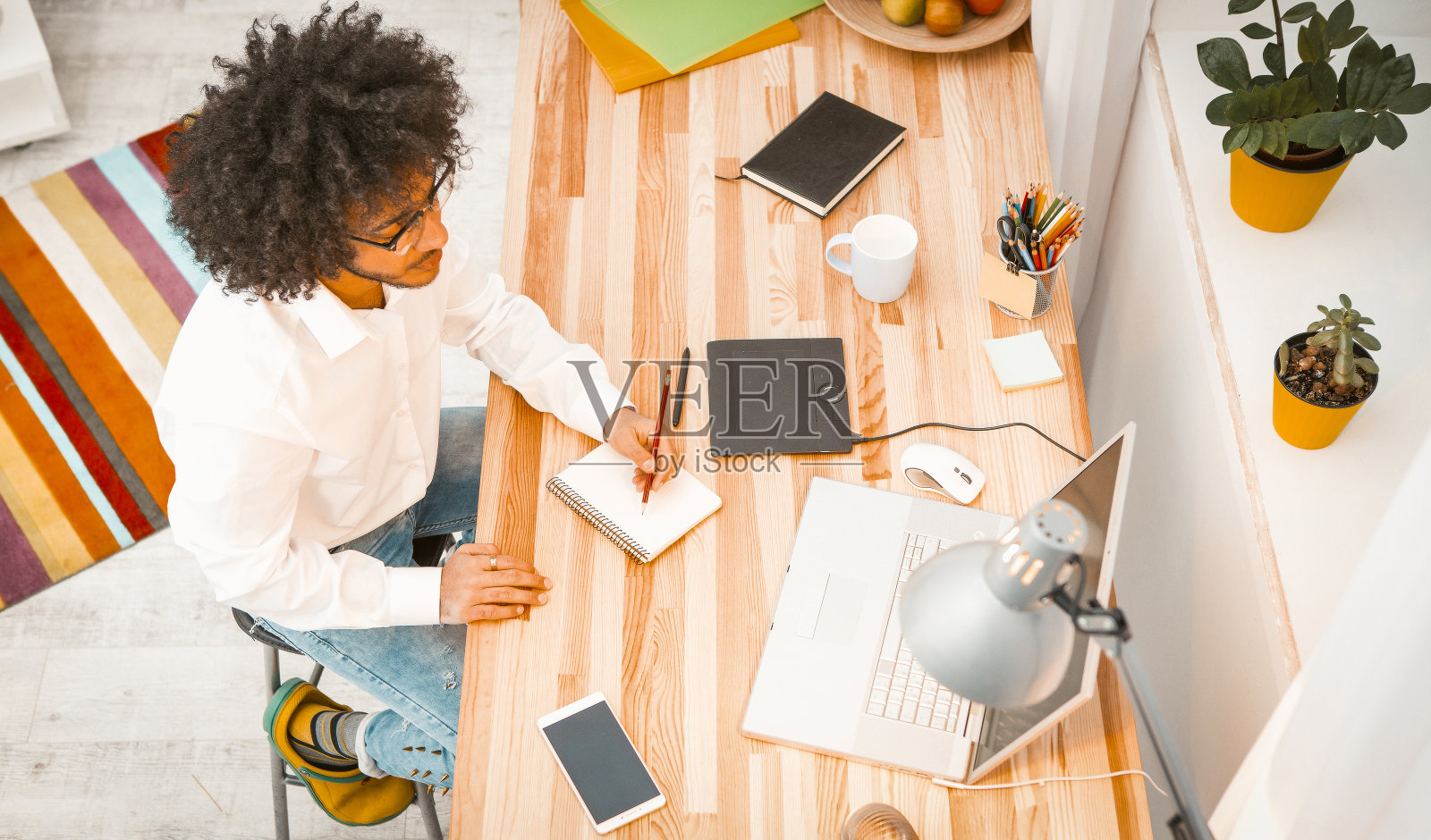 在家工作的文案撰写人，在笔记本上写笔记，看着笔记本电脑。戴眼镜的阿拉伯学生在工作或学习照片摄影图片