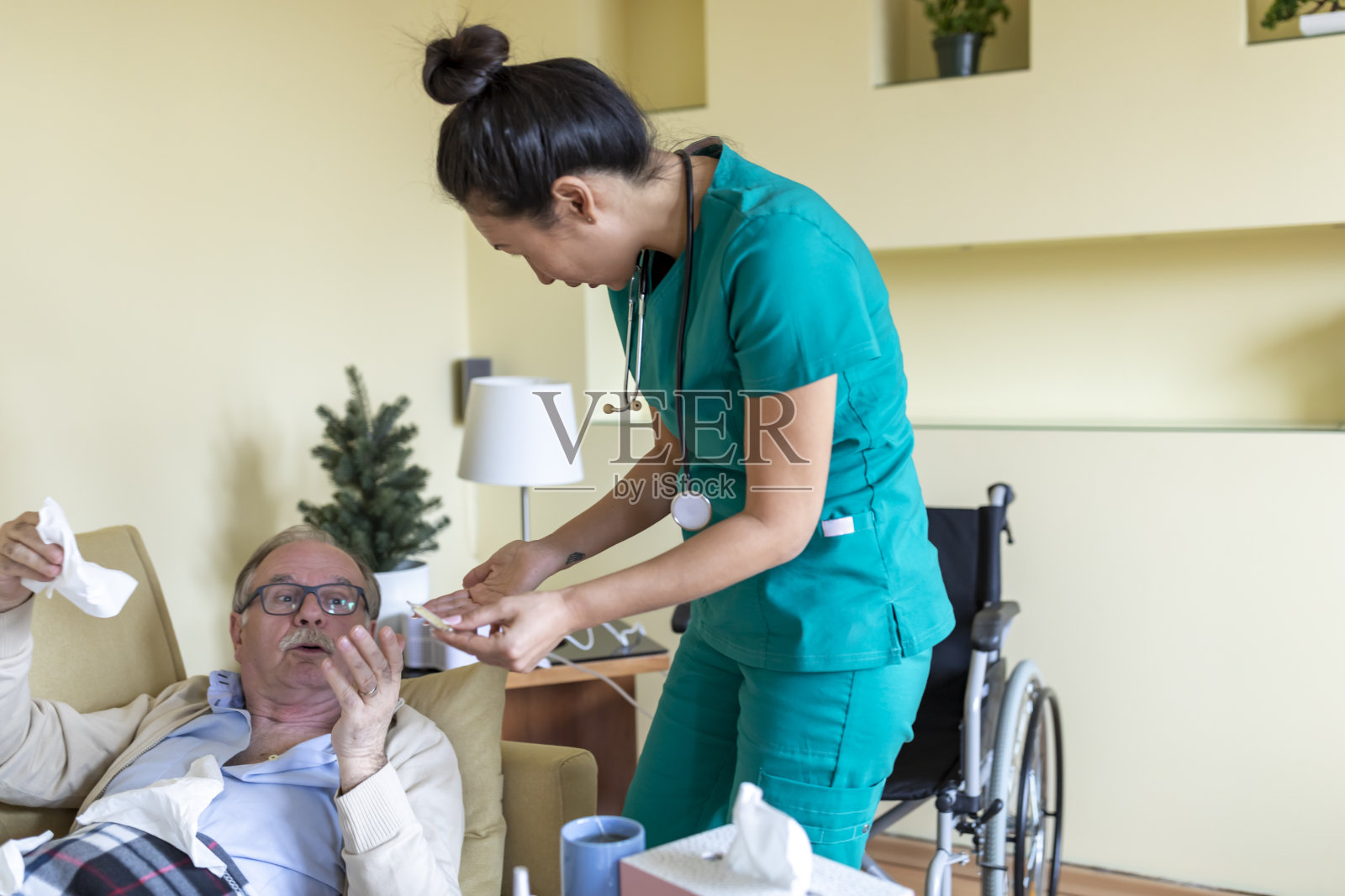 一名患季节性流感的男子正躺在床上接受一名穿绿色制服的护士的治疗。照片摄影图片