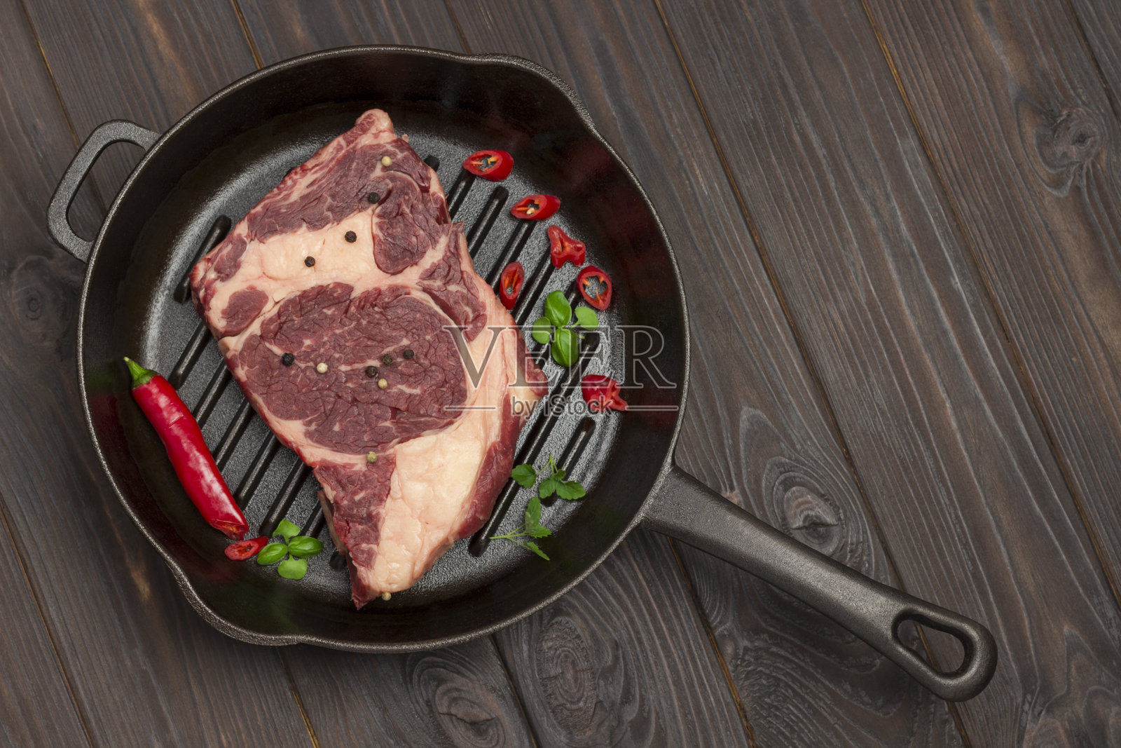 生肉。金属烤盘中的大理石牛排配上辣椒照片摄影图片