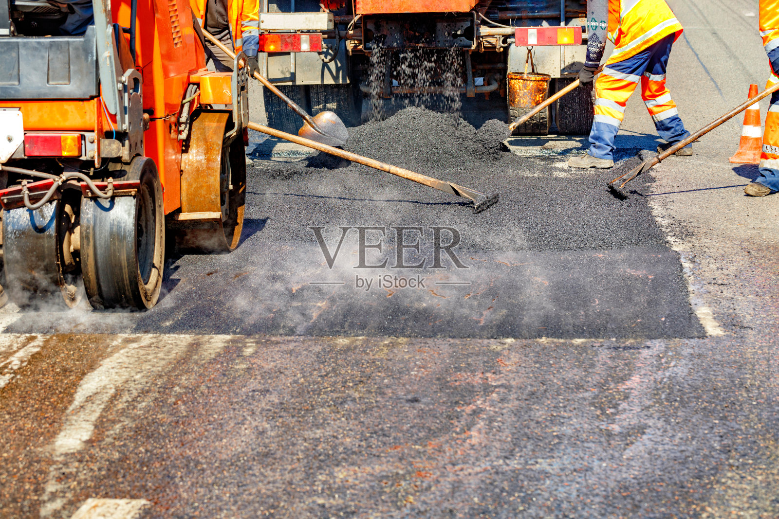 一组道路工人使用手工工具和道路设备修复部分道路。照片摄影图片