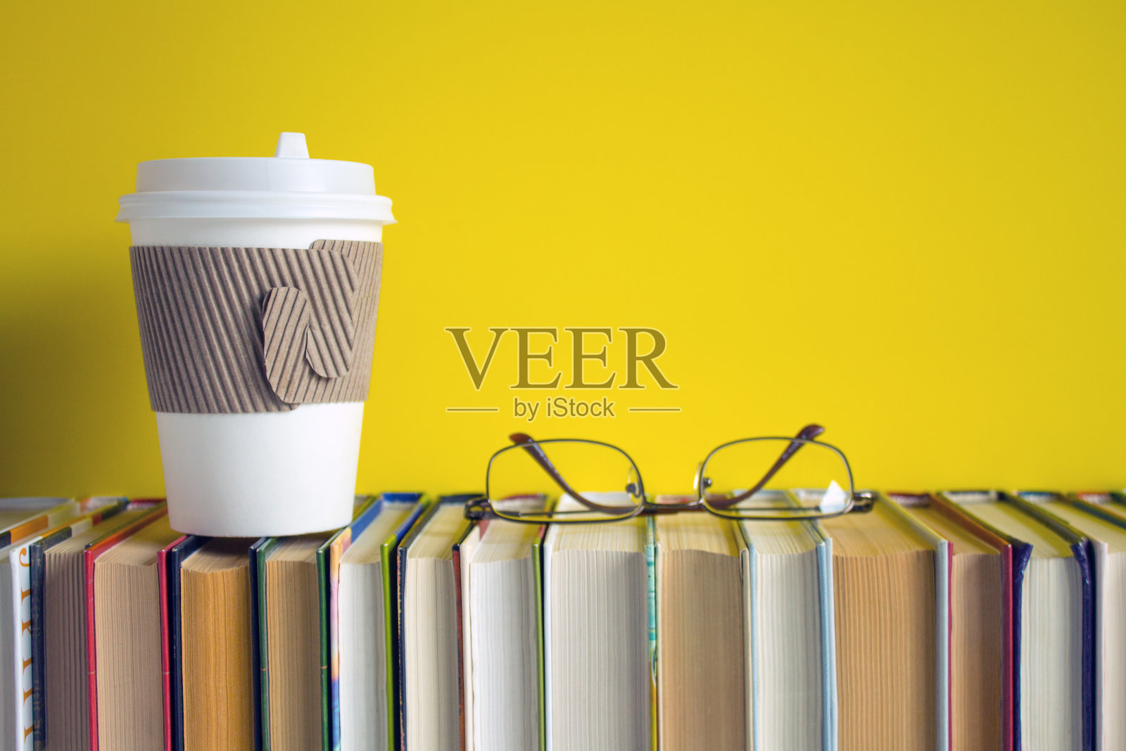 一排整齐的书和一杯一次性咖啡照片摄影图片