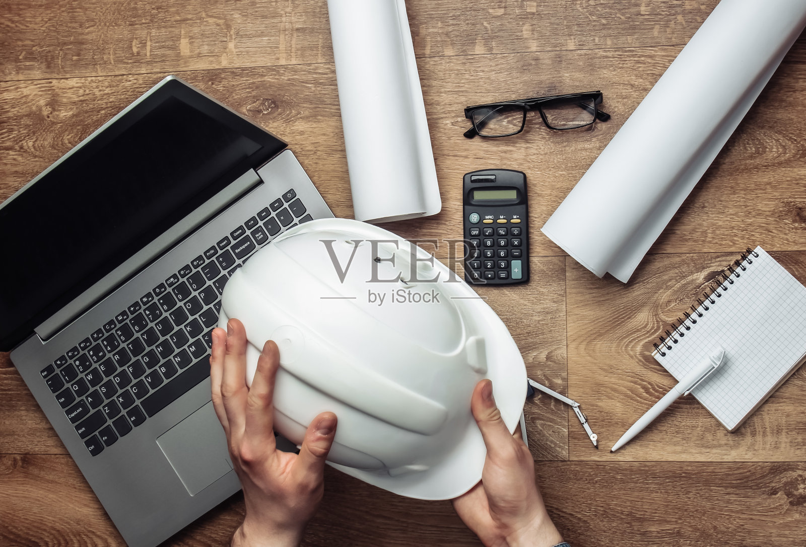 工程师的工作空间。男人的手握建筑头盔的背景工作场所。俯视图照片摄影图片