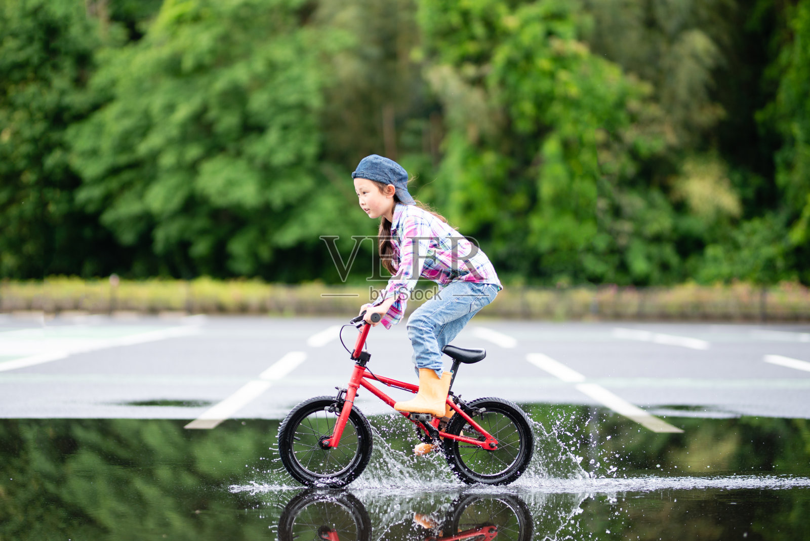 小女孩在水坑里骑自行车照片摄影图片