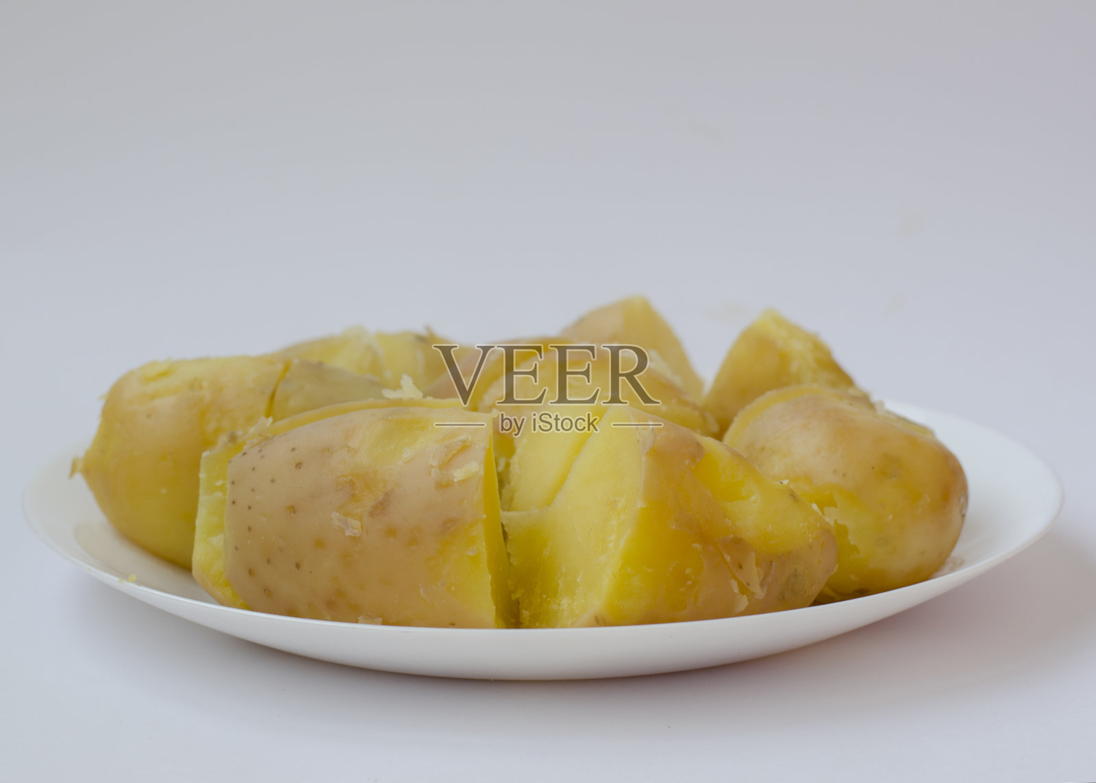 白底煮土豆的盘子。简单健康的食物。自制土豆菜肴。照片摄影图片