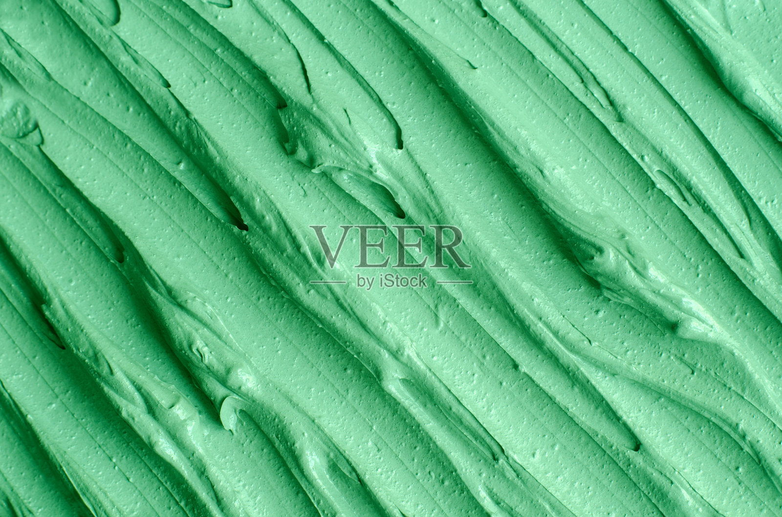 绿色化妆粘土(海带面膜、面霜、螺旋藻体贴)质地近距离，选择性聚焦。抽象的背景与画笔笔触。照片摄影图片