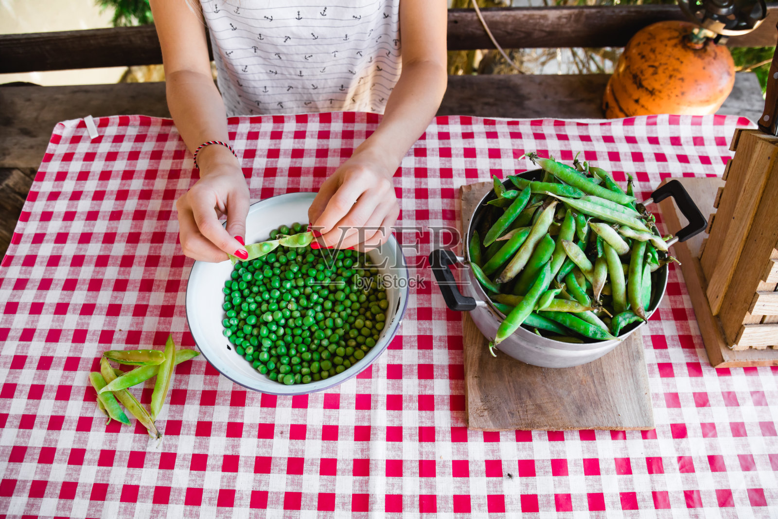 一名妇女正在准备新鲜的有机豌豆，并将其从壳中取出。照片摄影图片