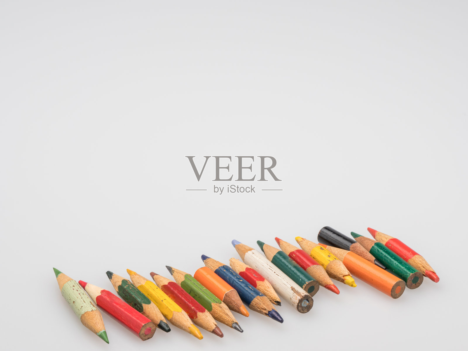 旧彩色铅笔的残骸。白色背景上的小铅笔。照片摄影图片