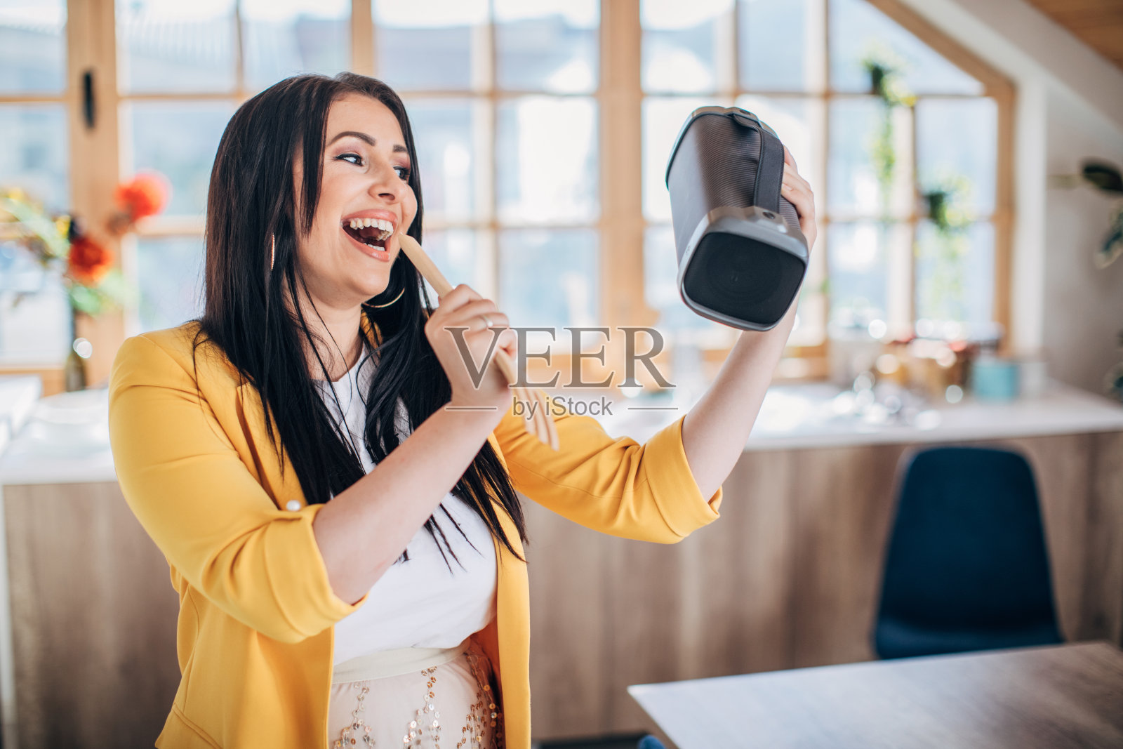 一个拿着无线蓝牙扬声器在家唱歌跳舞的女人照片摄影图片