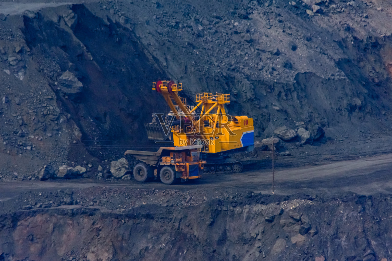 在采石场，重型挖掘机装载着巨大的自卸车铁矿石照片摄影图片