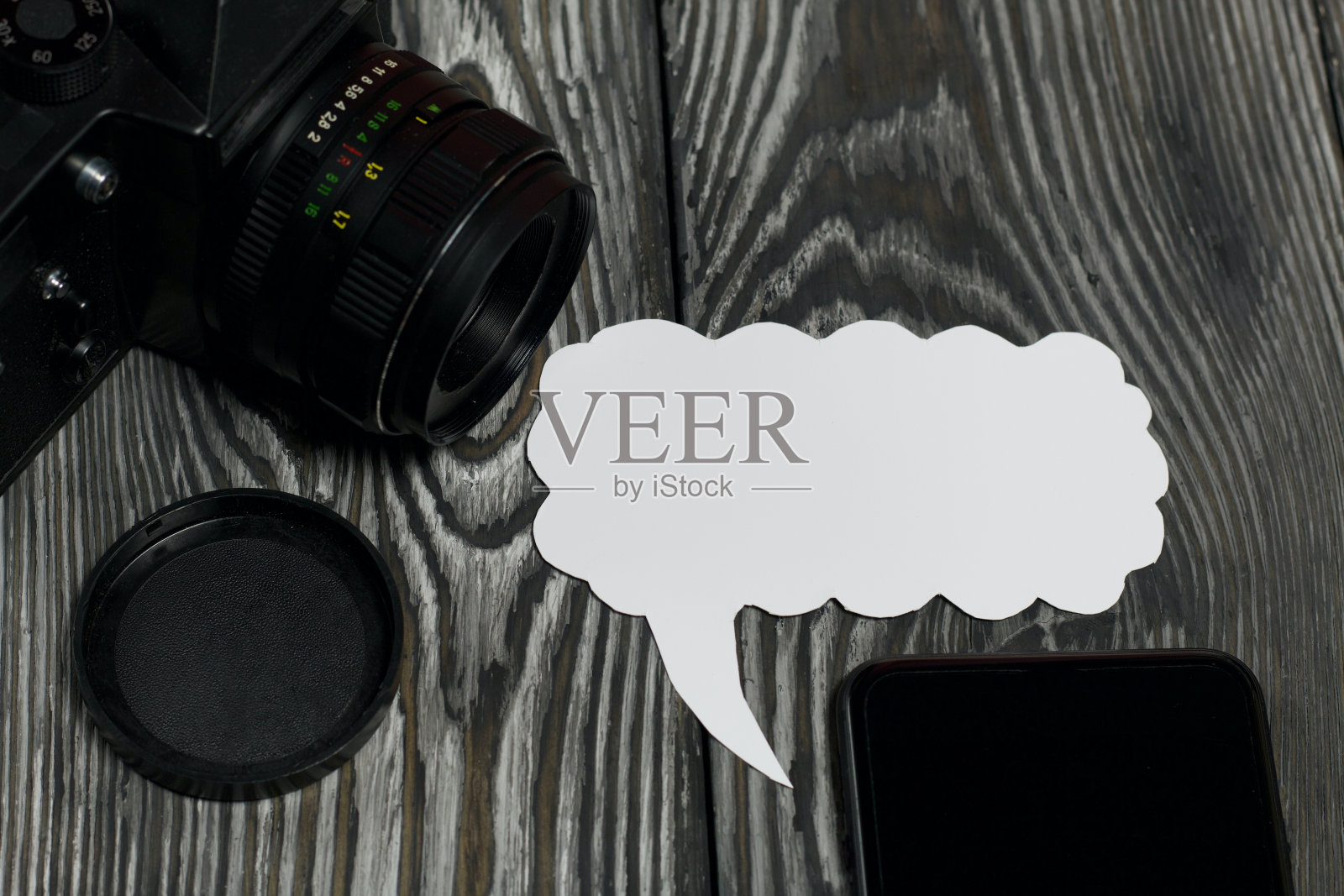 博客相机和智能手机。靠近演讲气泡。以刷过的松木板为背景。照片摄影图片