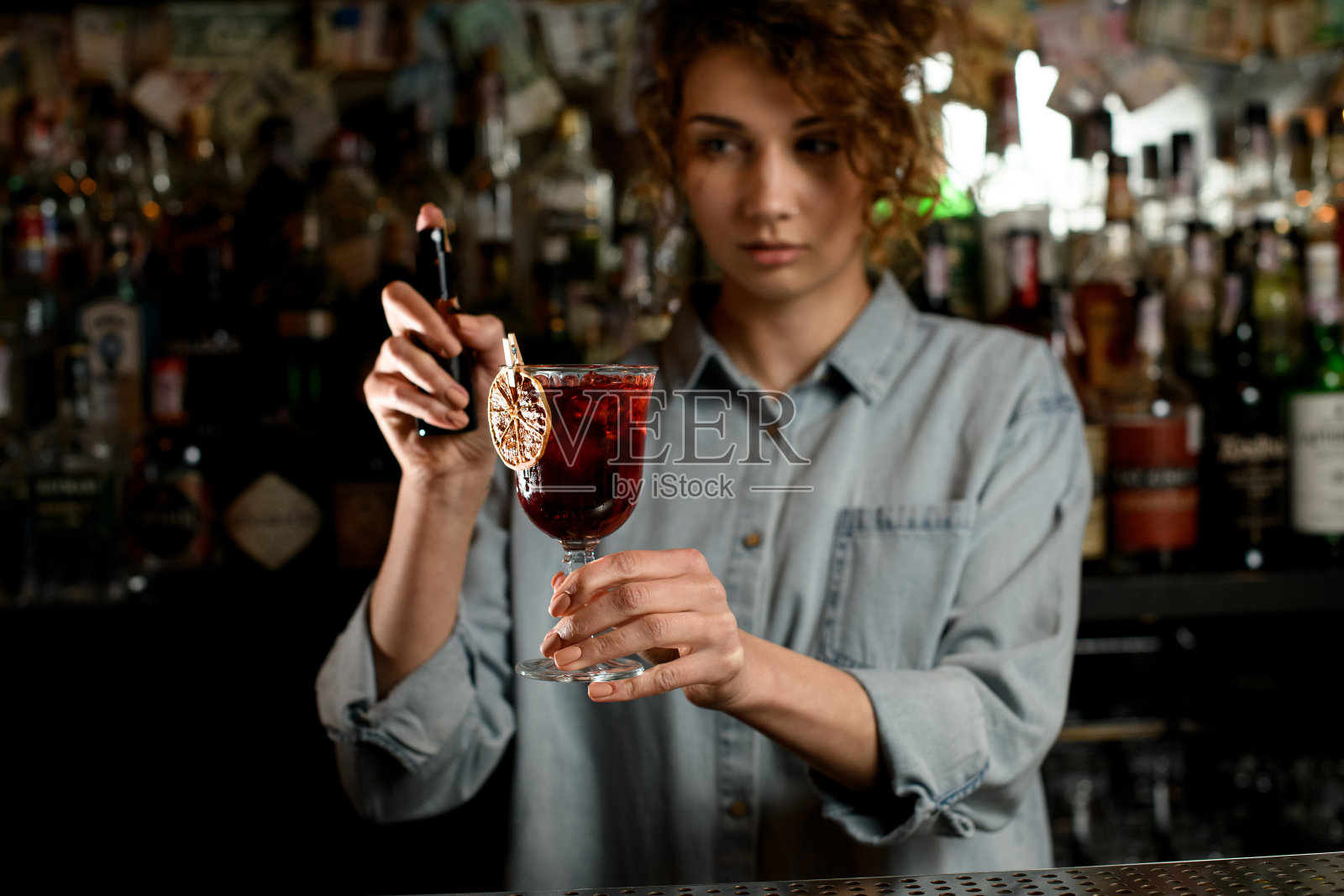 年轻的女酒保手里拿着一杯酒照片摄影图片