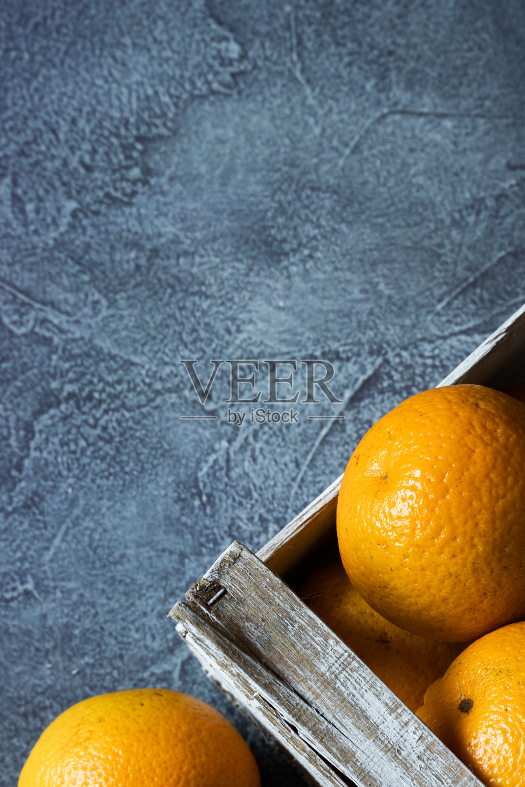 在蓝色背景的木盒子里的新鲜橙子的特写。运输和运送装在木箱里的橙子。前视图。副本的空间。照片摄影图片