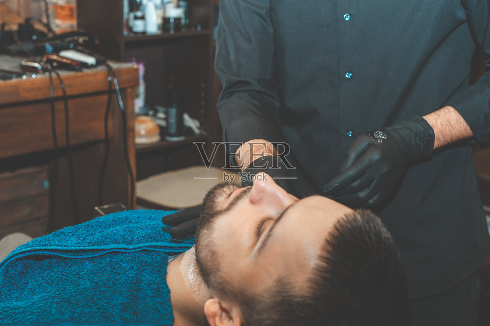 男士美容店。在理发店里刮胡子。理发师用剃刀和剪子剪他的胡子。残酷的发型。理发师设备。有选择性的重点。照片摄影图片