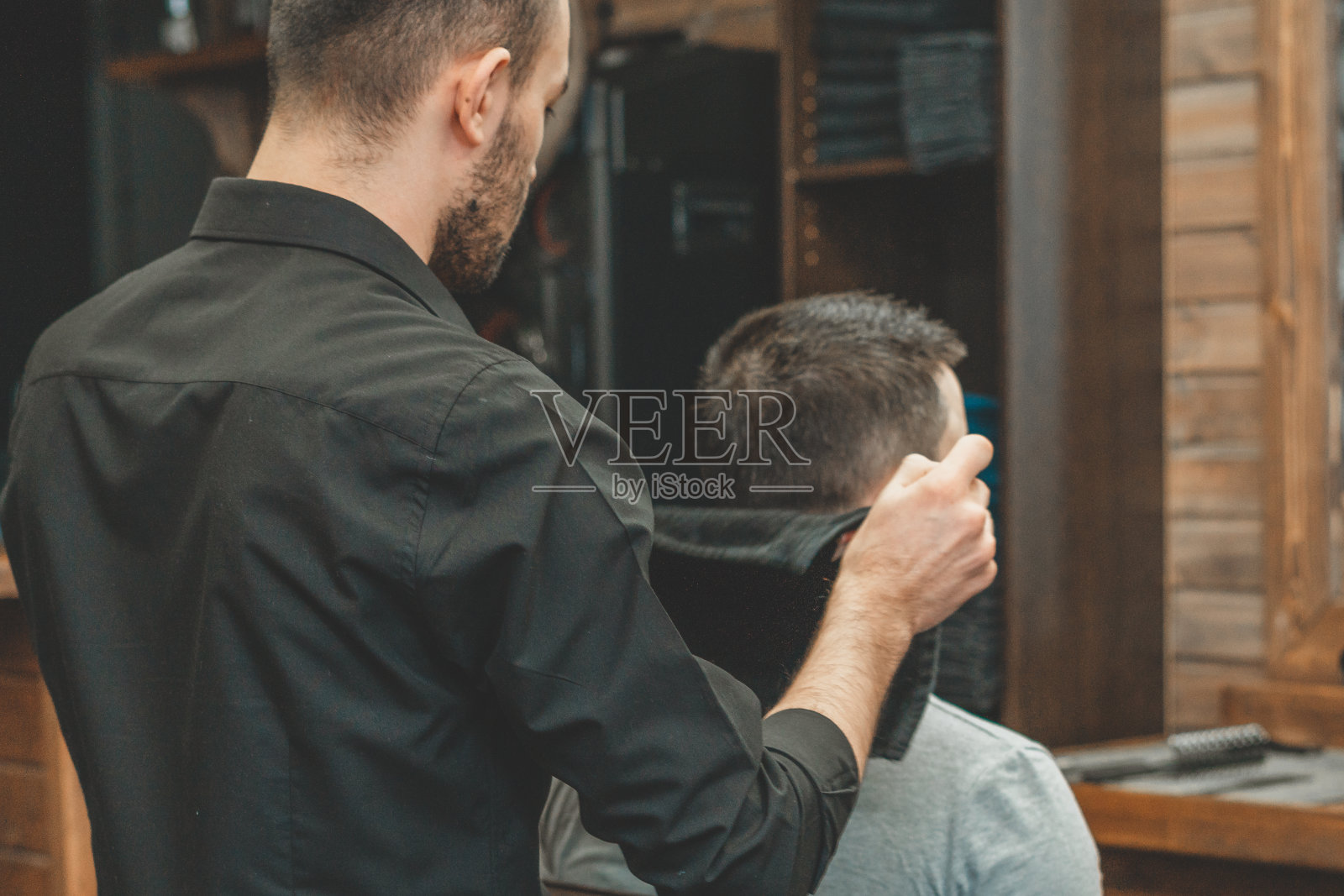 去理发店理发。理发师为客户理发。为男人设计发型的过程。理发店里的一个男人。不久的计划。设备设计师。有选择性的重点照片摄影图片