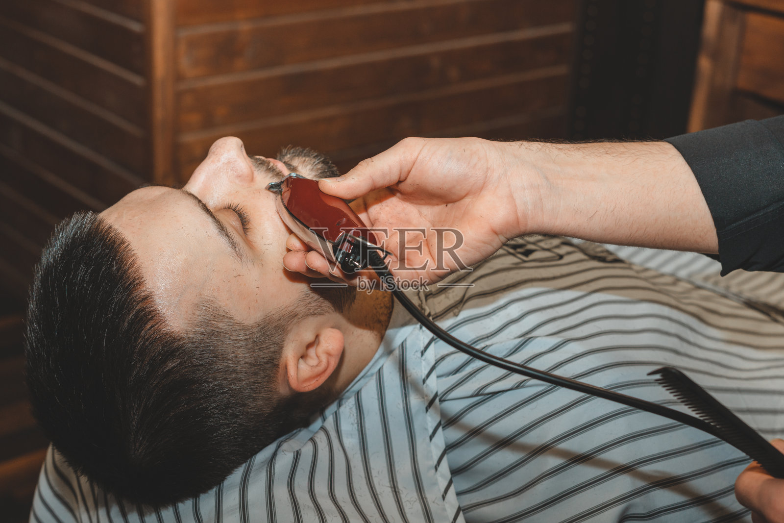 男士美容店。在理发店里刮胡子。理发师用剃刀和剪子剪他的胡子。残酷的发型。理发师设备。有选择性的重点。照片摄影图片