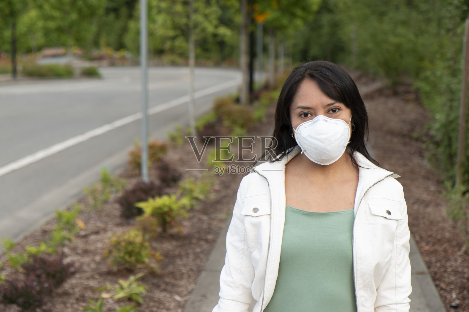 年轻的西班牙妇女戴着N95口罩走在街上照片摄影图片