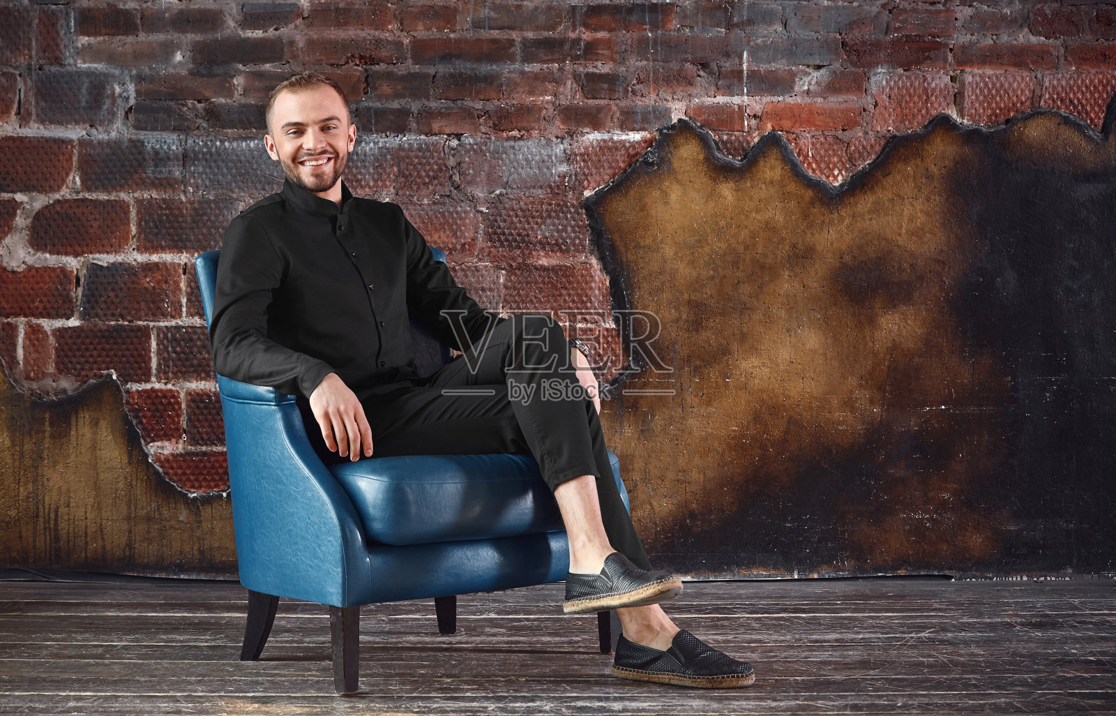 一个年轻人坐在阁楼房间的扶手椅上，正看着摄像机。面对困难，不怕困难。承担责任。空间的副本照片摄影图片