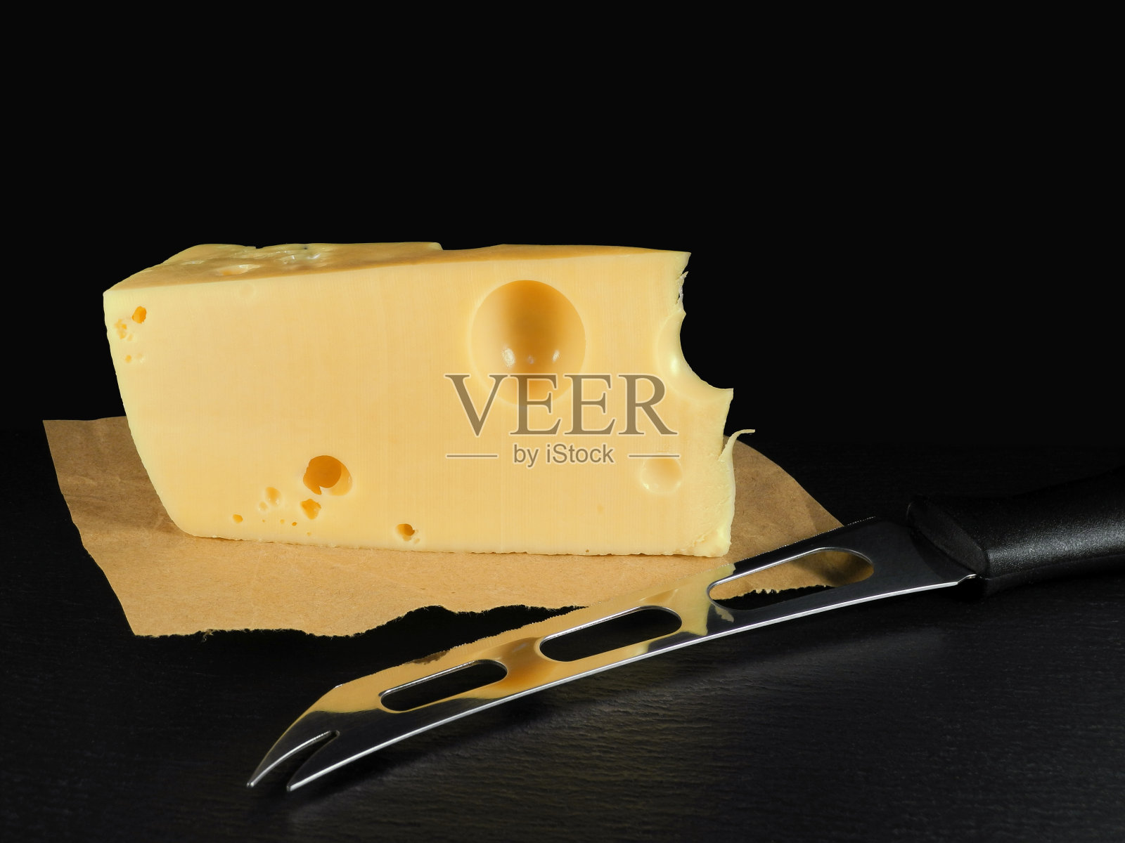 黑色背景上用特殊刀切的一块奶酪照片摄影图片