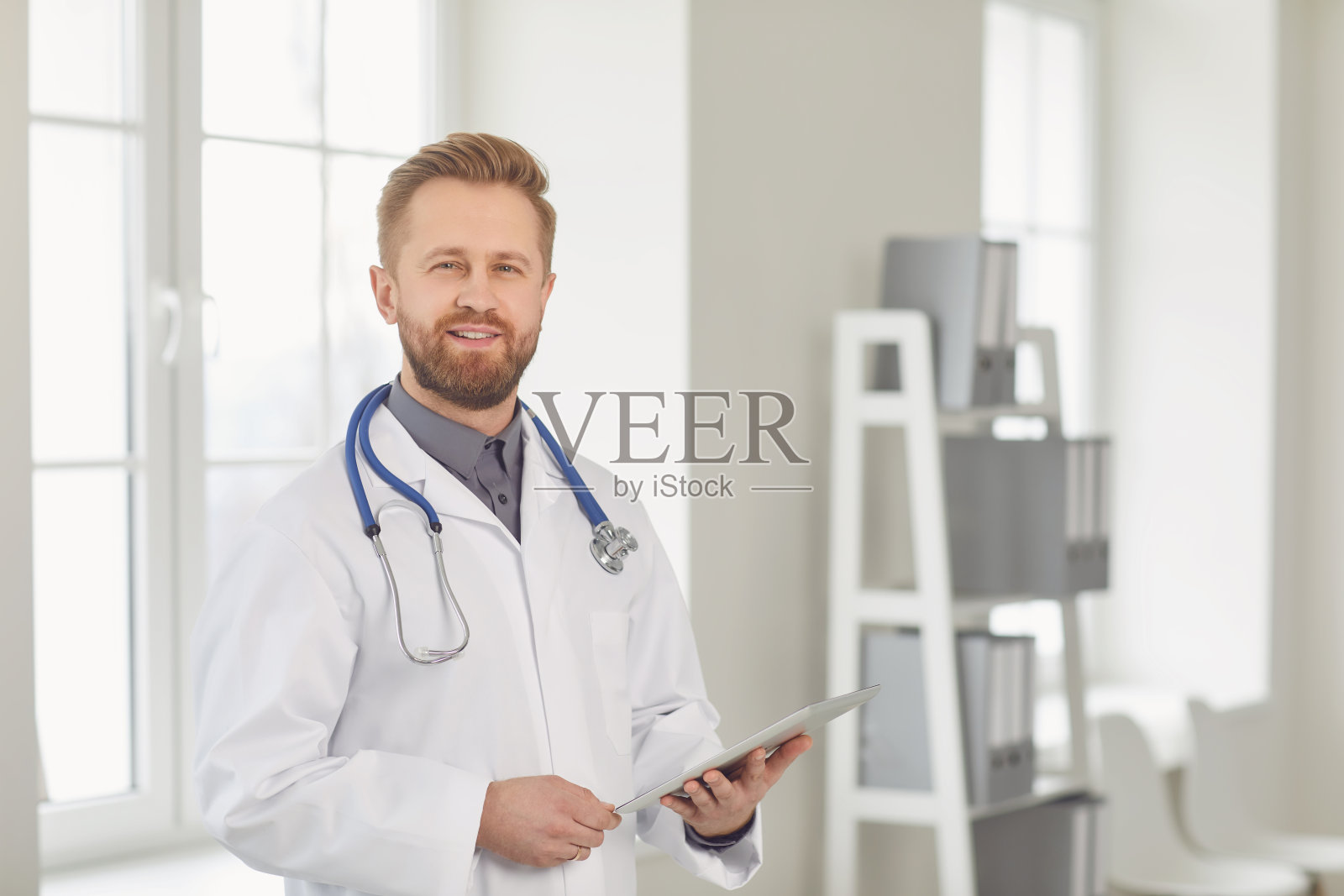 男医生小儿科医生站在医院的白色办公室里。照片摄影图片