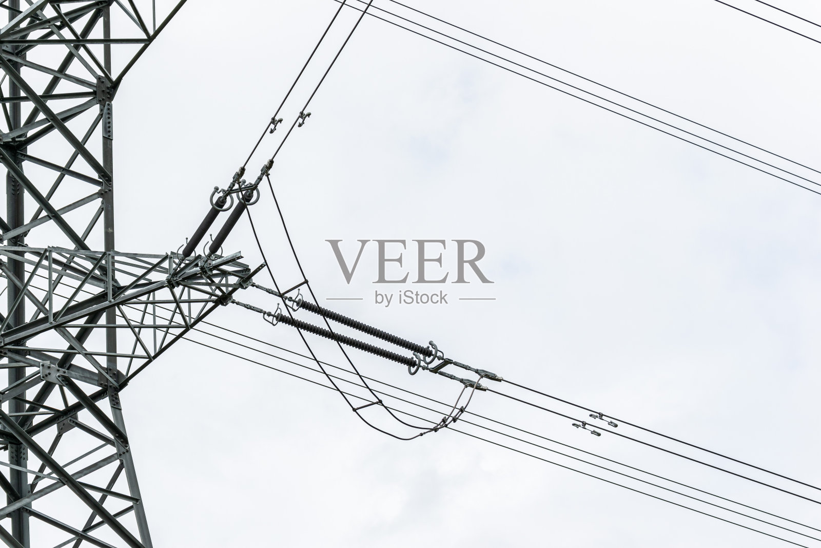 在蓝天的映衬下，输电塔上的电线向不同的方向散开。照片摄影图片