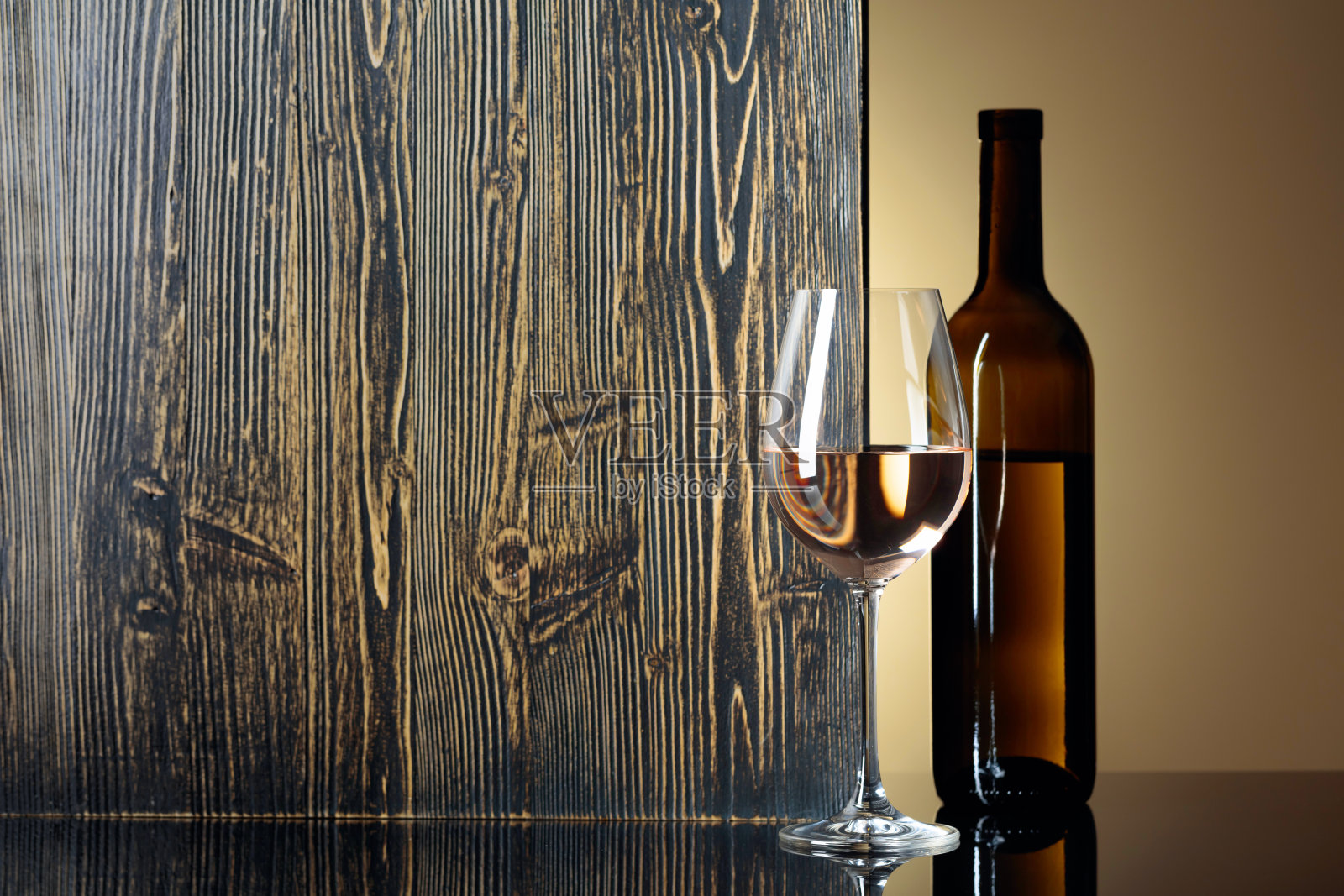 黑桌子上放着一瓶和一杯白葡萄酒。照片摄影图片