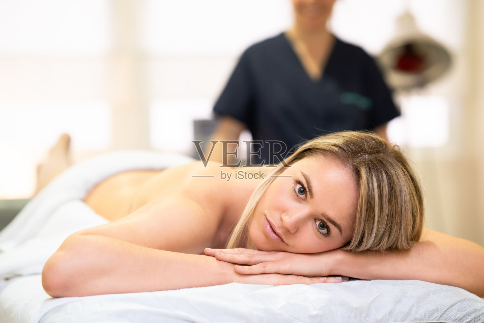 一个女人躺在理疗中心的担架上。照片摄影图片