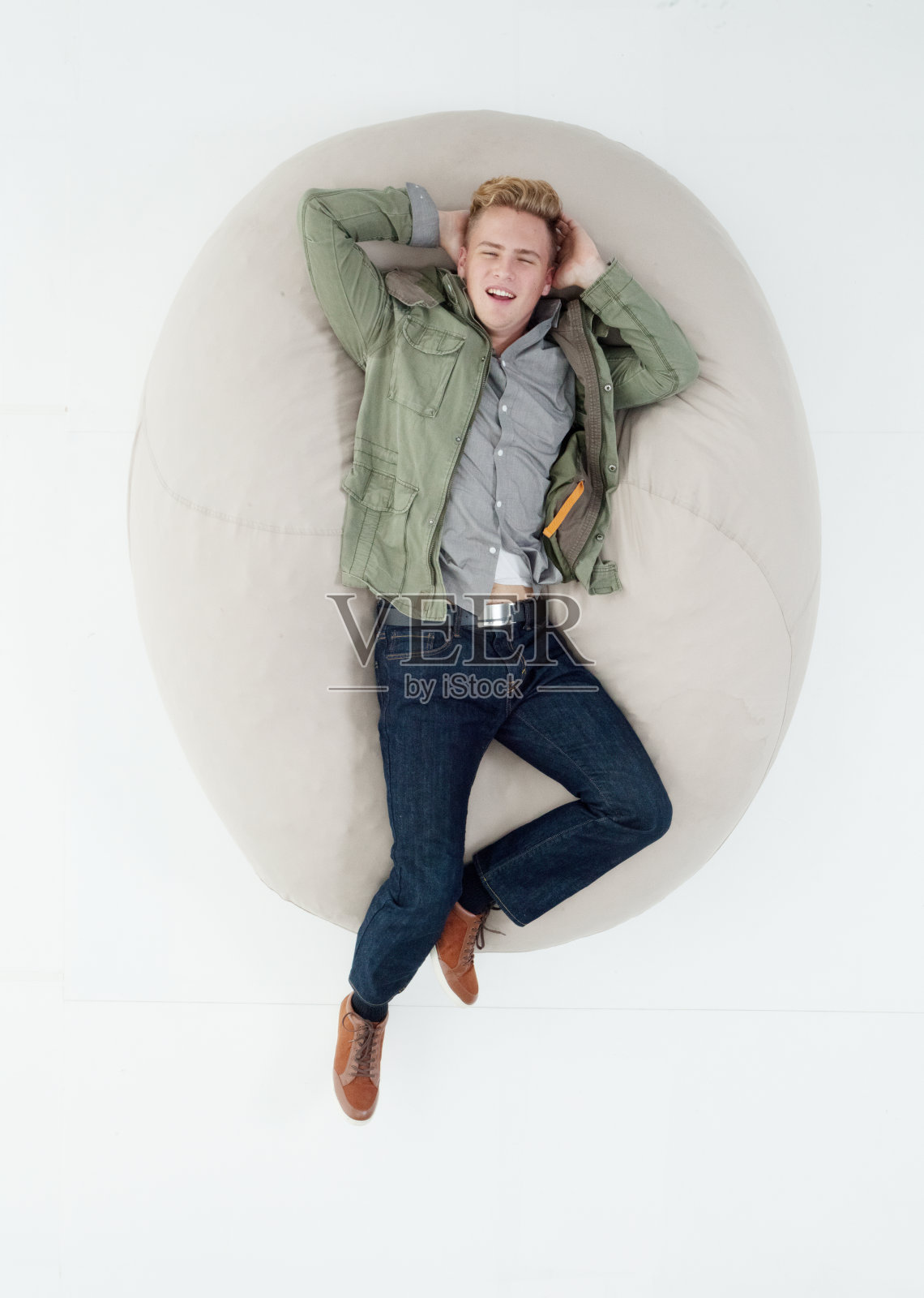 白人男孩躺在白色背景下，穿着裤子照片摄影图片