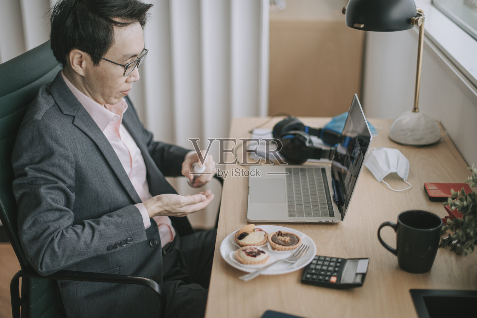 一名亚裔华人中年白领在工作站前用洗手液洗手照片摄影图片