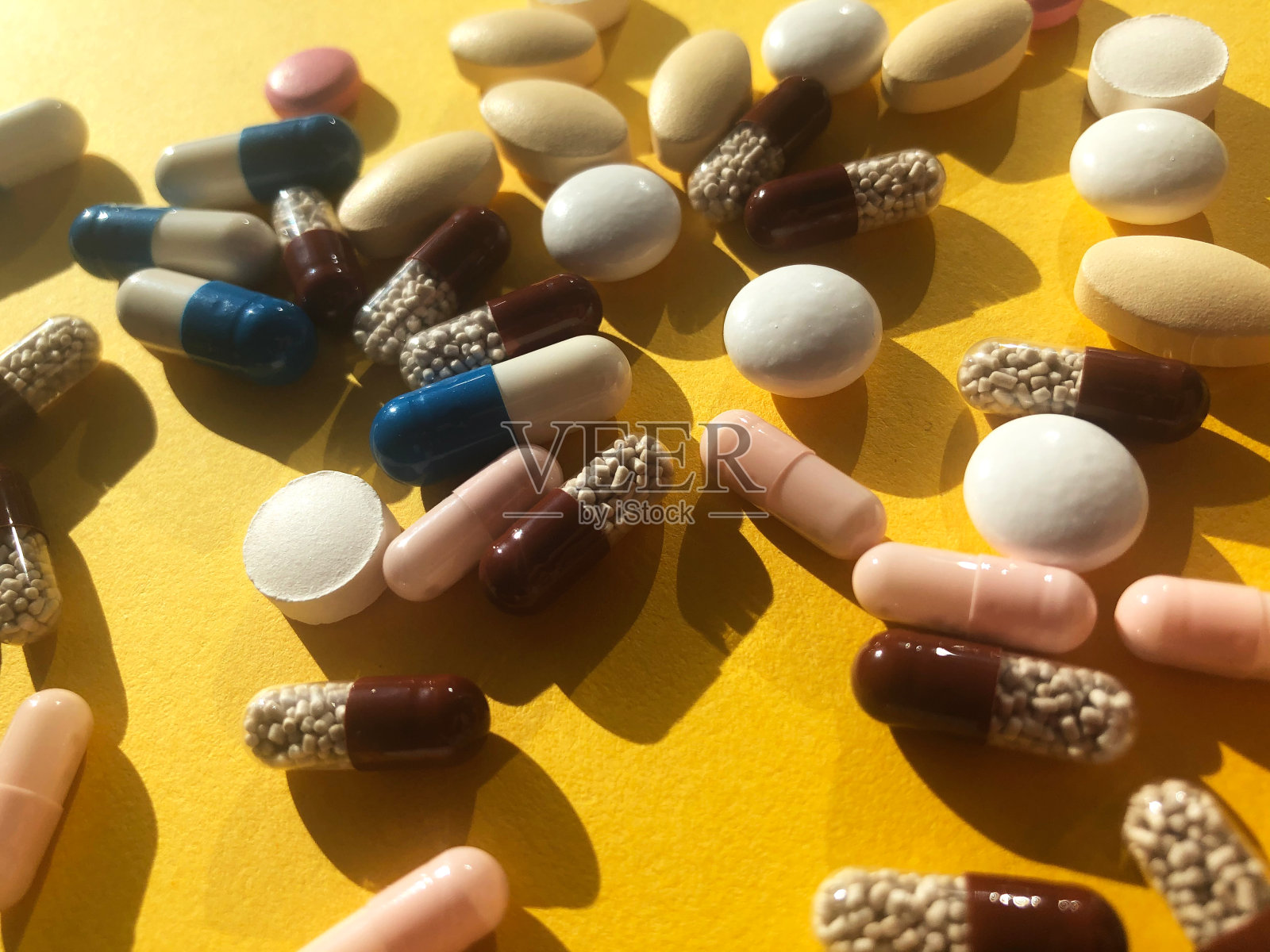 黄色背景上有很多五颜六色的药丸。照片摄影图片