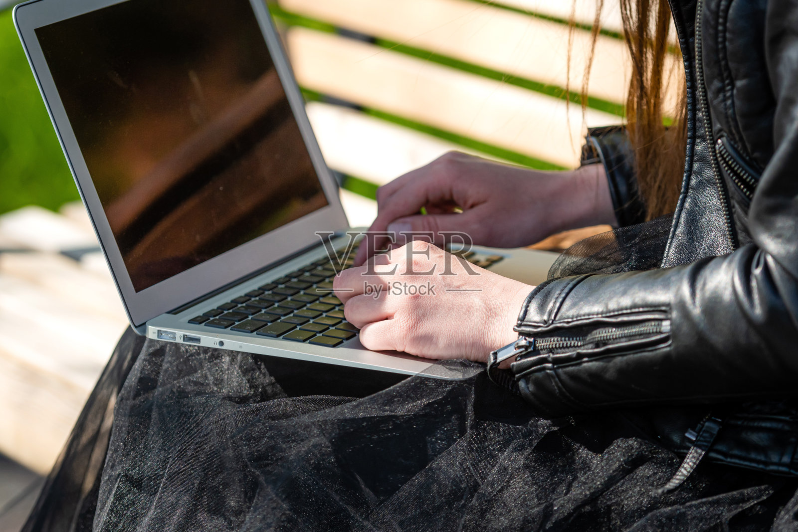女人在街道的长椅上使用笔记本电脑，女博主在键盘上打字，在任何远离家庭办公室的地方工作照片摄影图片