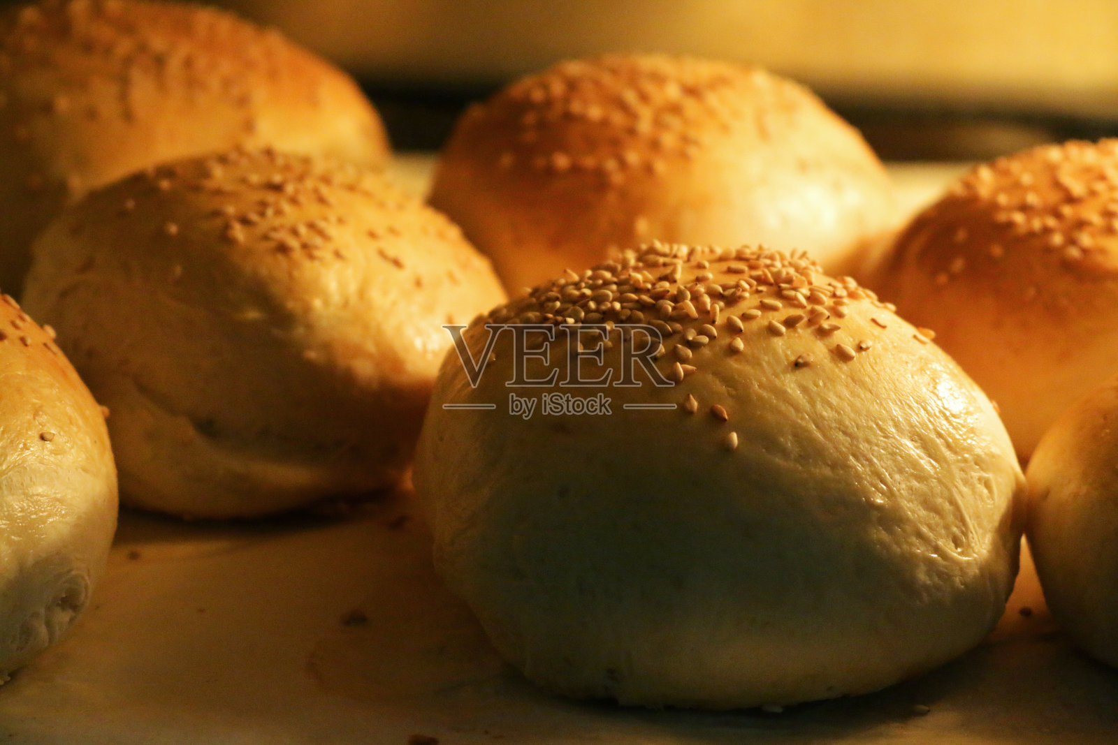 这是在热烤箱里烤撒着芝麻的自制白面包卷的特写，家庭烘焙照片摄影图片