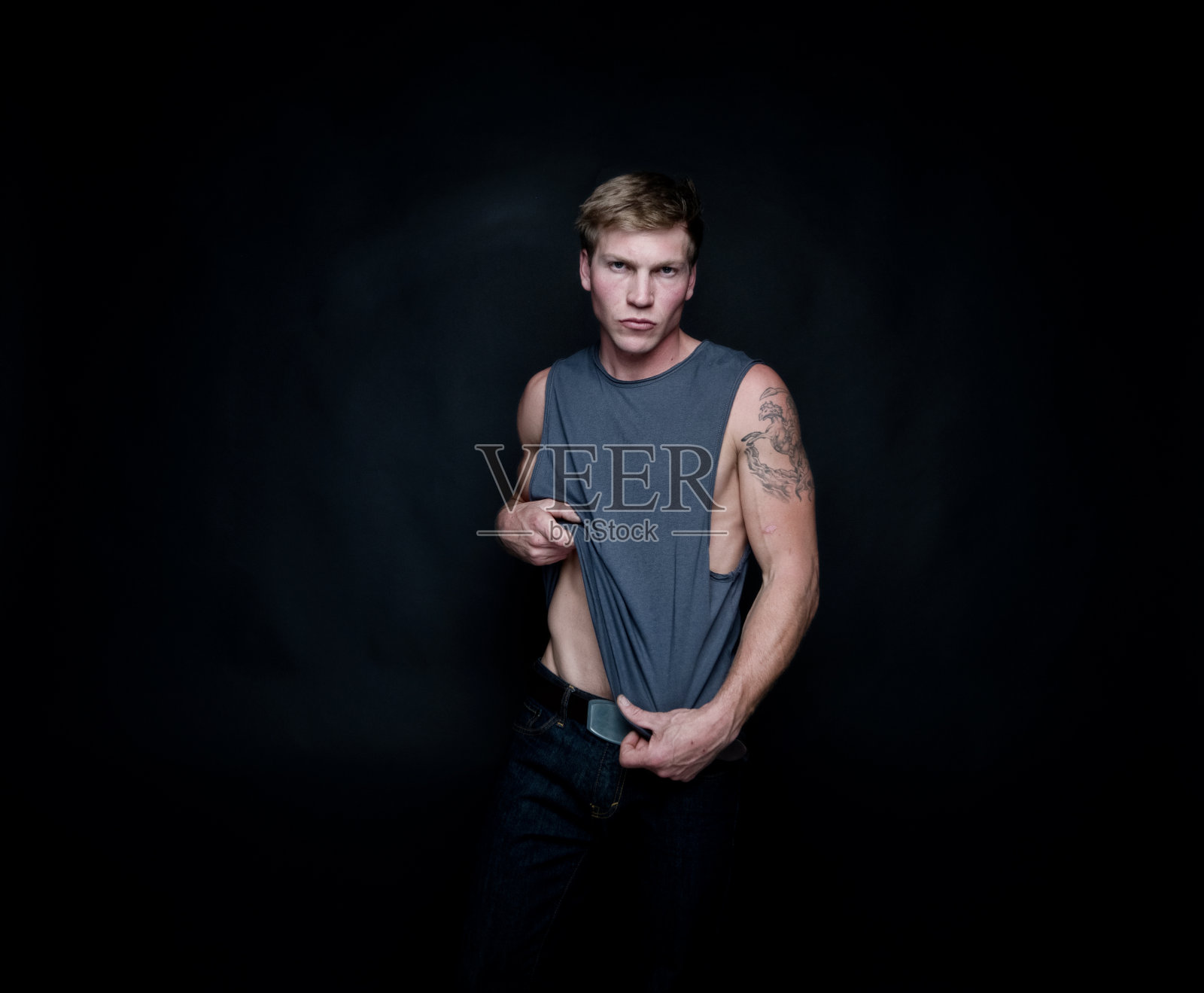 白人男性在黑色背景下穿着无袖牛仔裤照片摄影图片