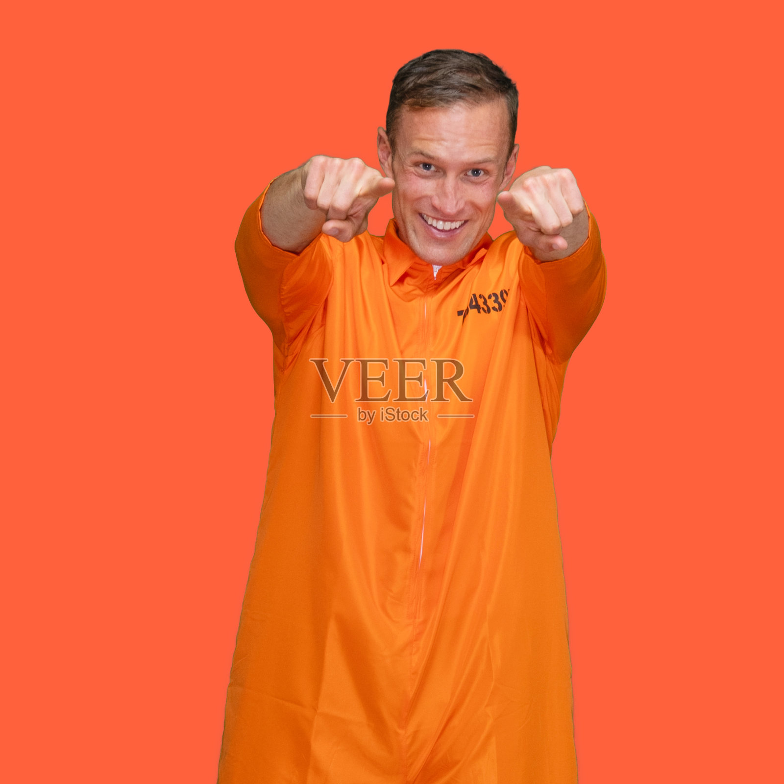 罪犯穿着连体衣站在橙色背景前照片摄影图片