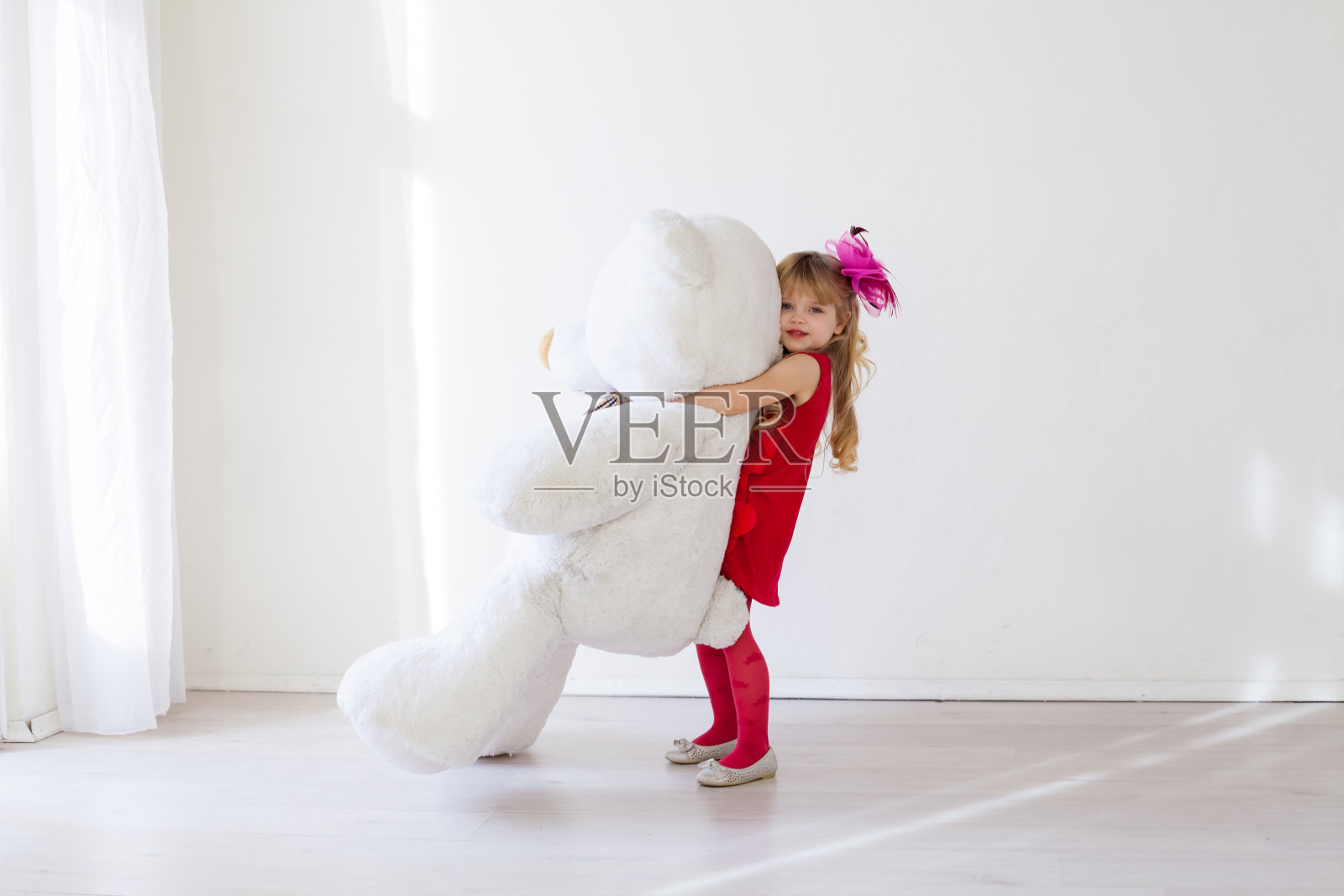 漂亮的小女孩拿着柔软的大玩具熊照片摄影图片