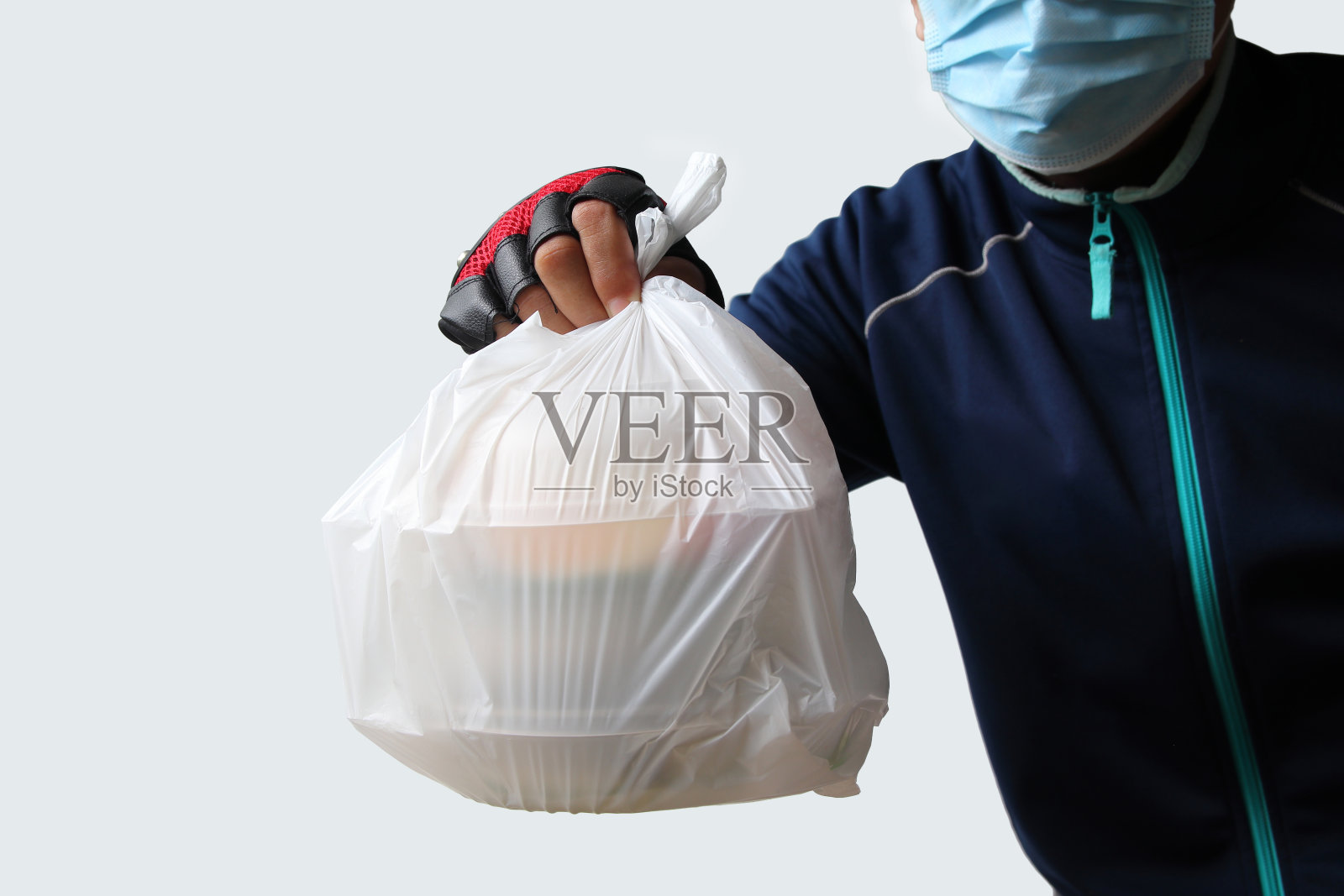 食品服务提供者戴着口罩。将装着食物的塑料袋寄给在网上订购食物的顾客照片摄影图片