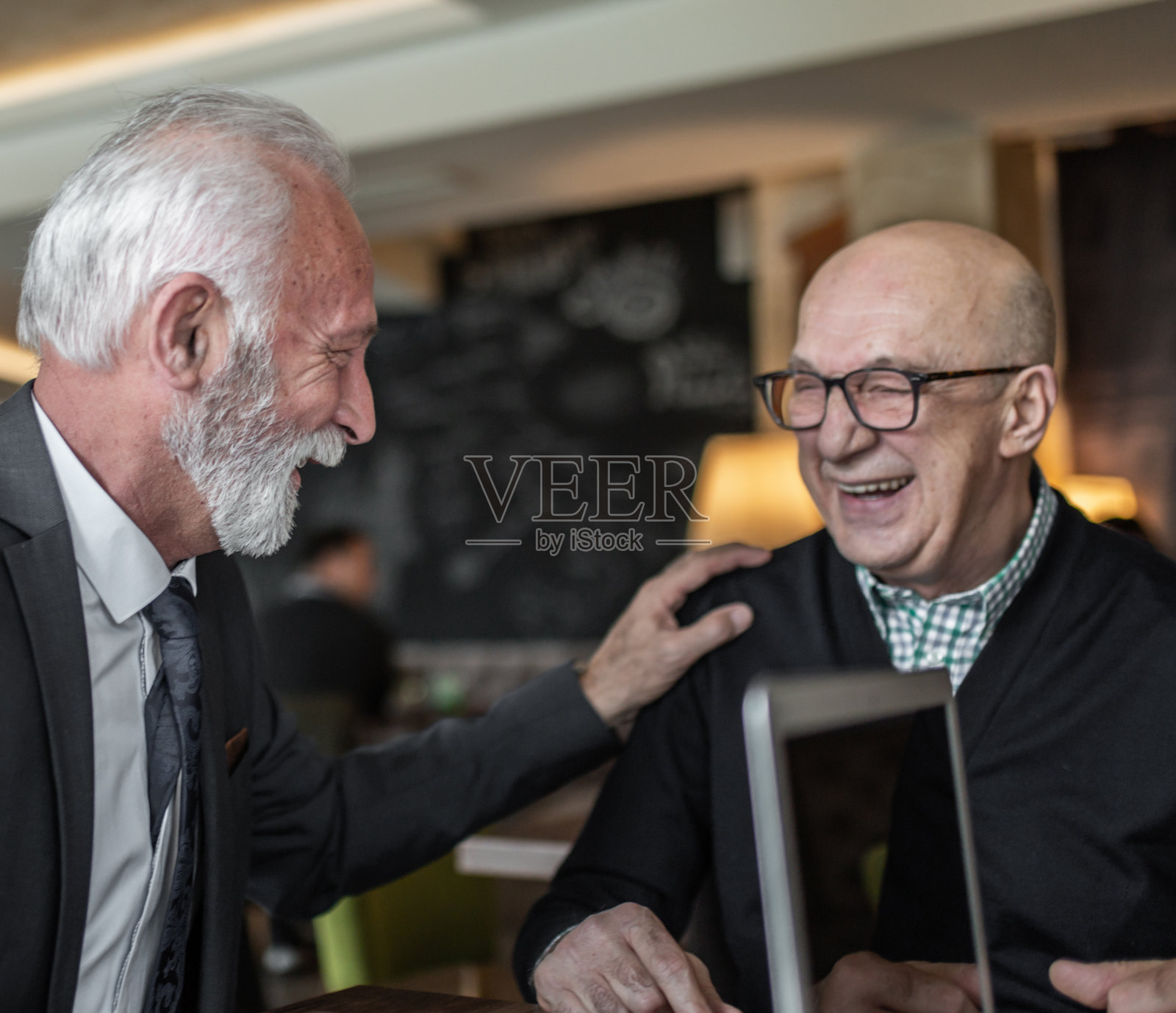 两名沉思的高级经理大笑着在室内使用笔记本电脑照片摄影图片