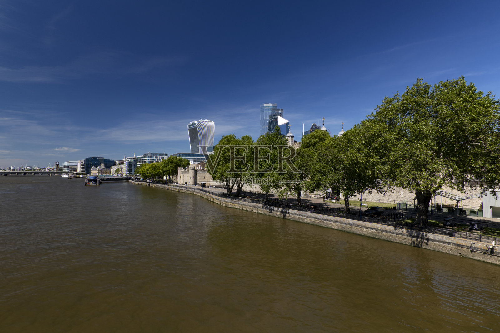 在一个阳光明媚的日子，从一座悬索桥上看到的泰晤士河和伦敦市中心金融区的景色。照片摄影图片