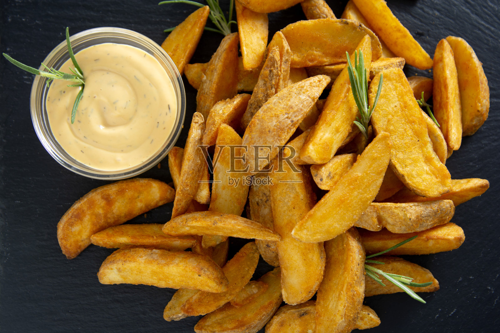 炸土豆配香草和酱汁。金色烤土豆，家庭快餐。照片摄影图片