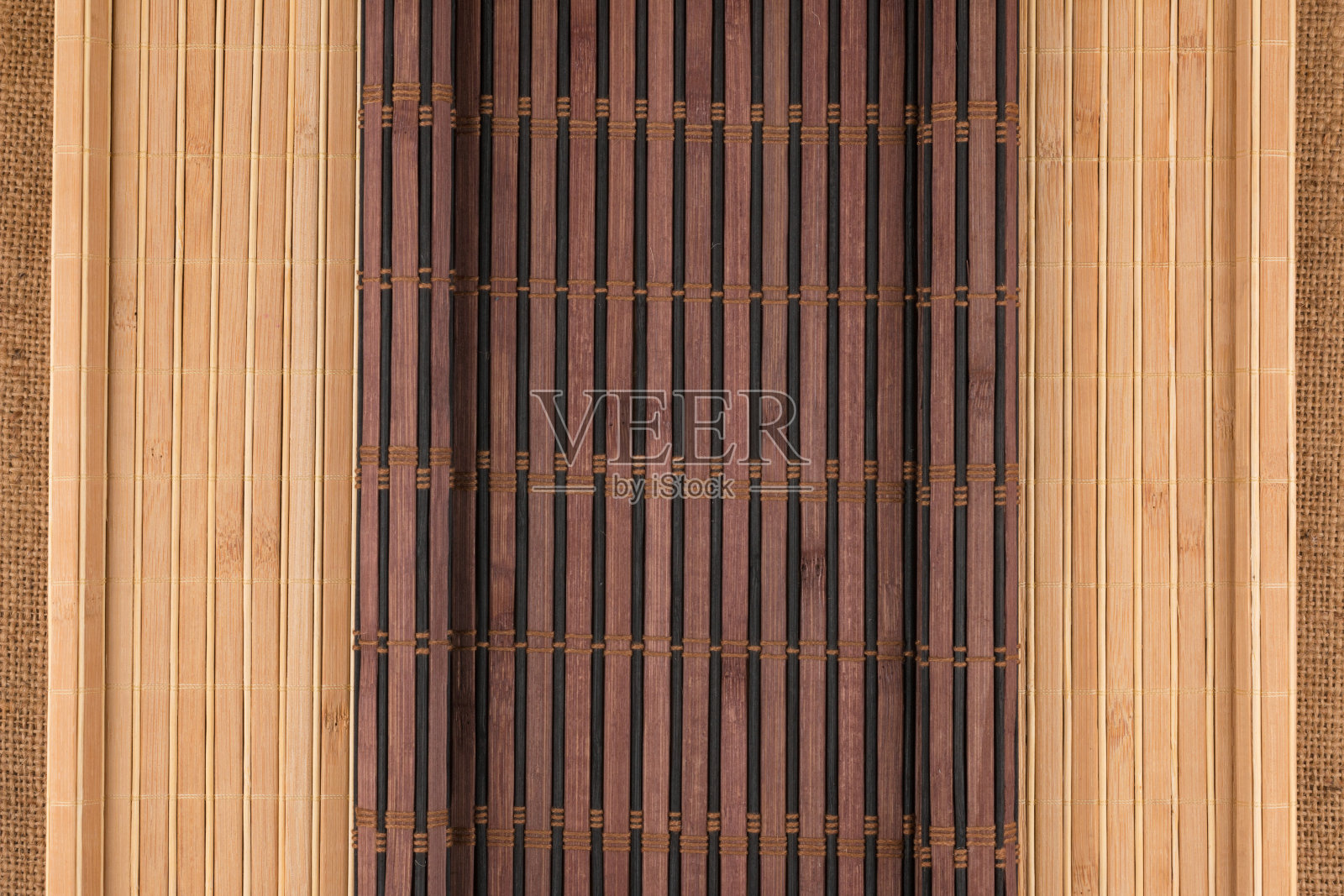 粗麻布上铺着黑亮的竹席，呈卷轴状。照片摄影图片