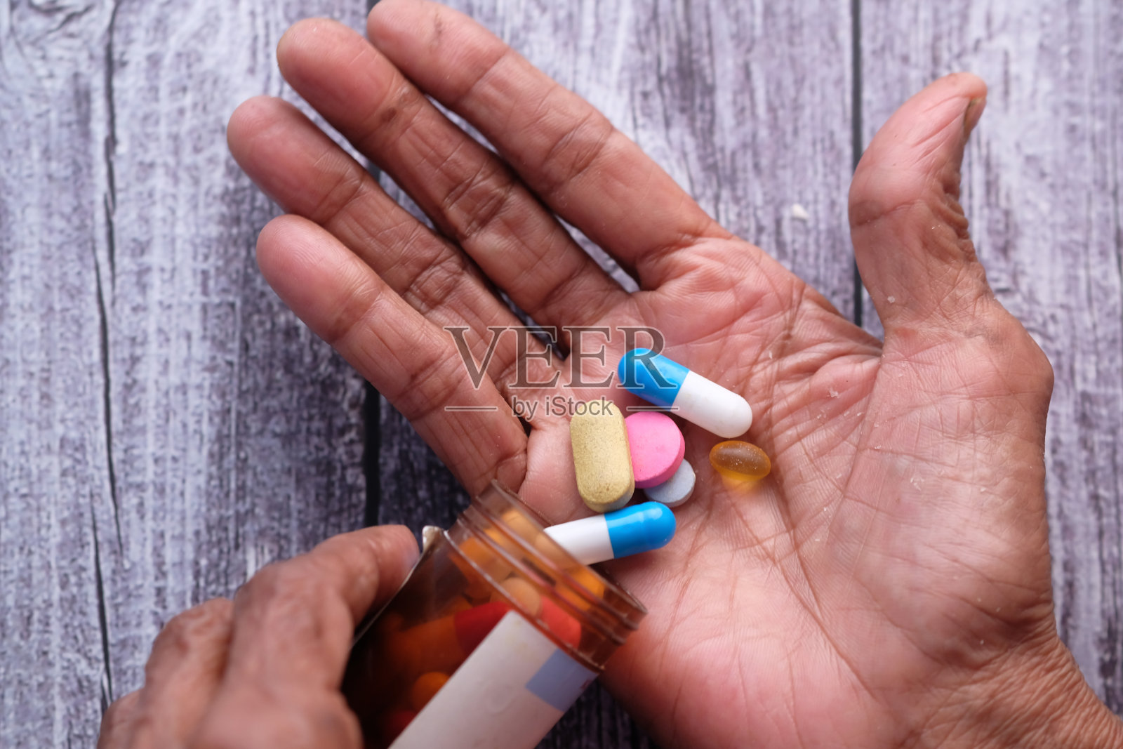 老年妇女从手头有复印空间的瓶子里倒药丸照片摄影图片