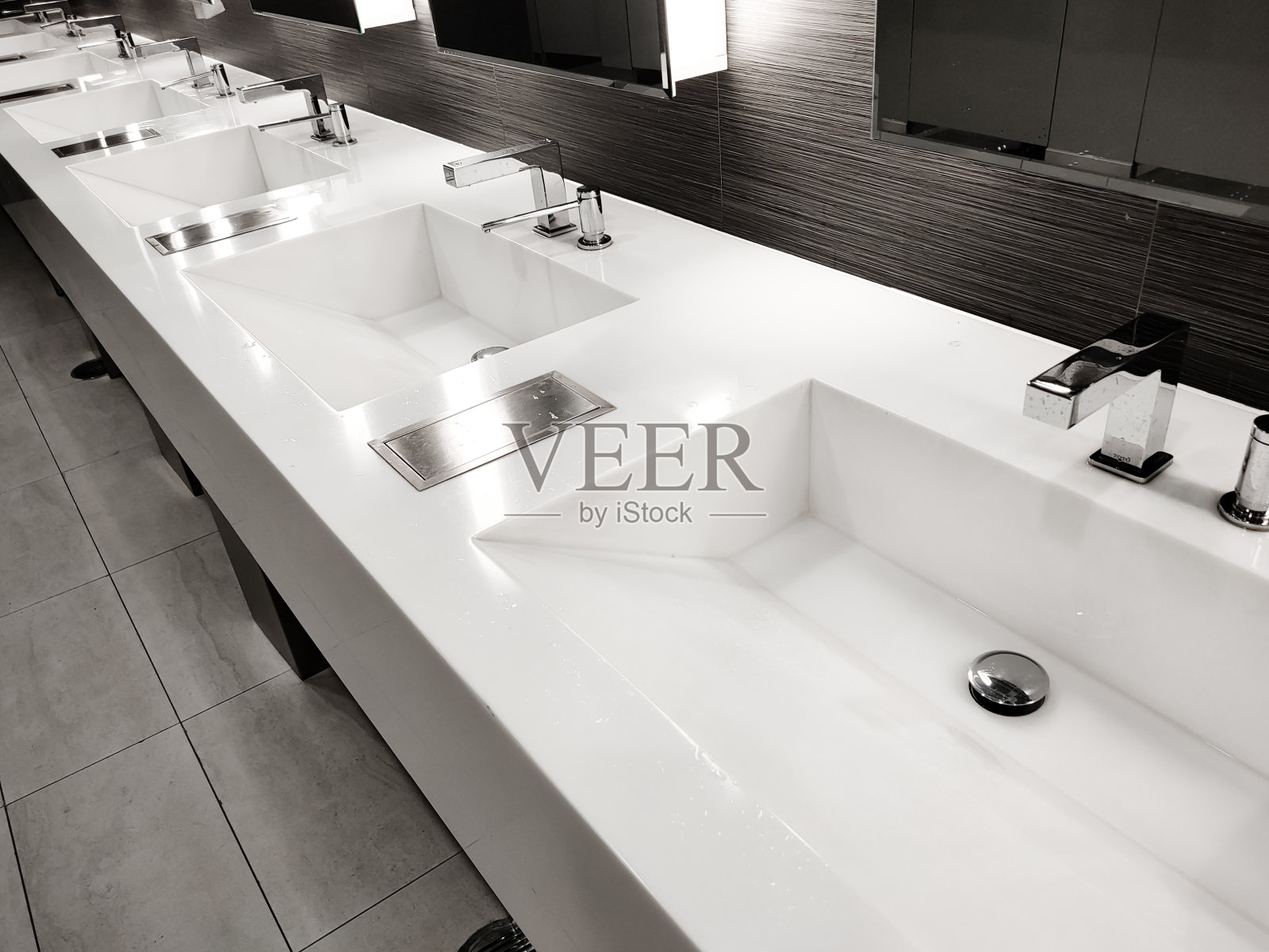 公共空厕所与盥洗架，婴儿更换器，厕所在镜子。配有镜子和灯光的白色水槽排。顶部横向查看拷贝空间照片摄影图片