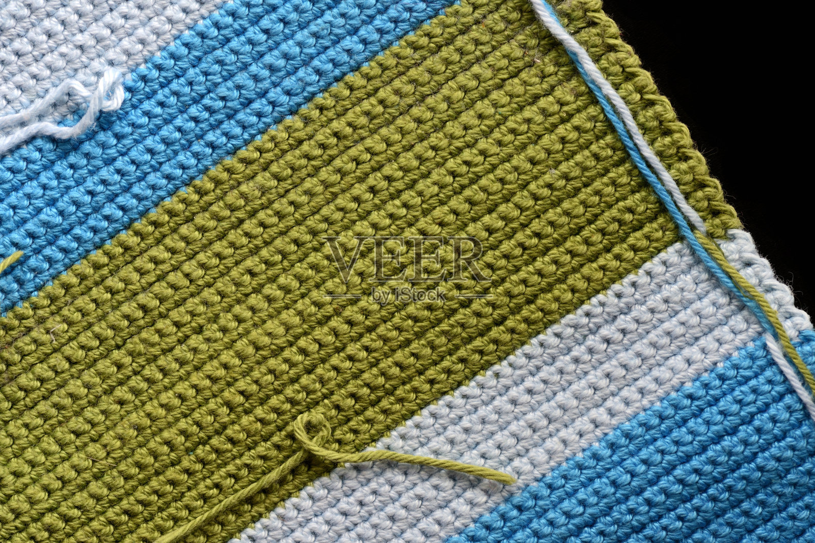从绿色，蓝色和浅蓝色线钩针织物碎片，特写，顶视图。抽象的背景。手工制作的概念照片摄影图片