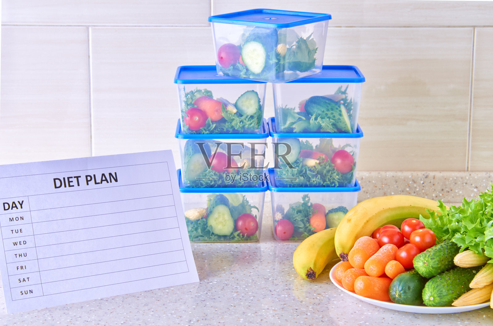 一个星期的饮食计划，在一张白色的桌子上，中间是一套装食物和食物的塑料容器。一周内适当的营养。照片摄影图片