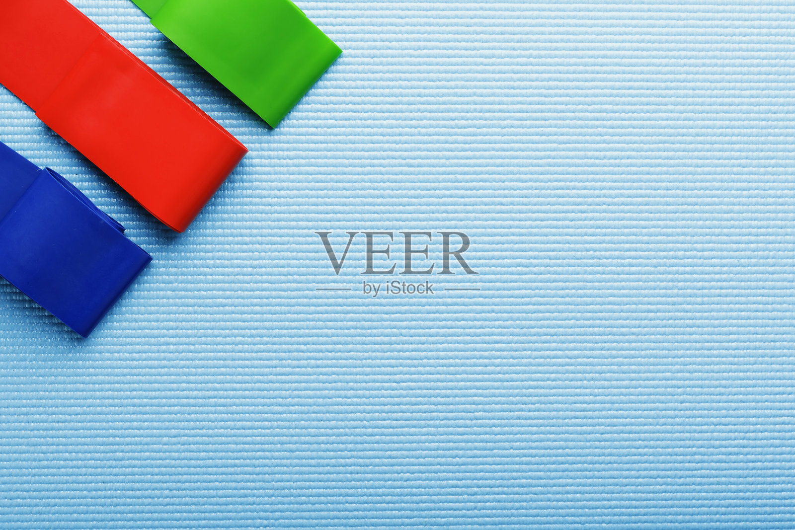 适合运动的不同颜色和负载的健身橡皮筋在蓝色背景。照片摄影图片