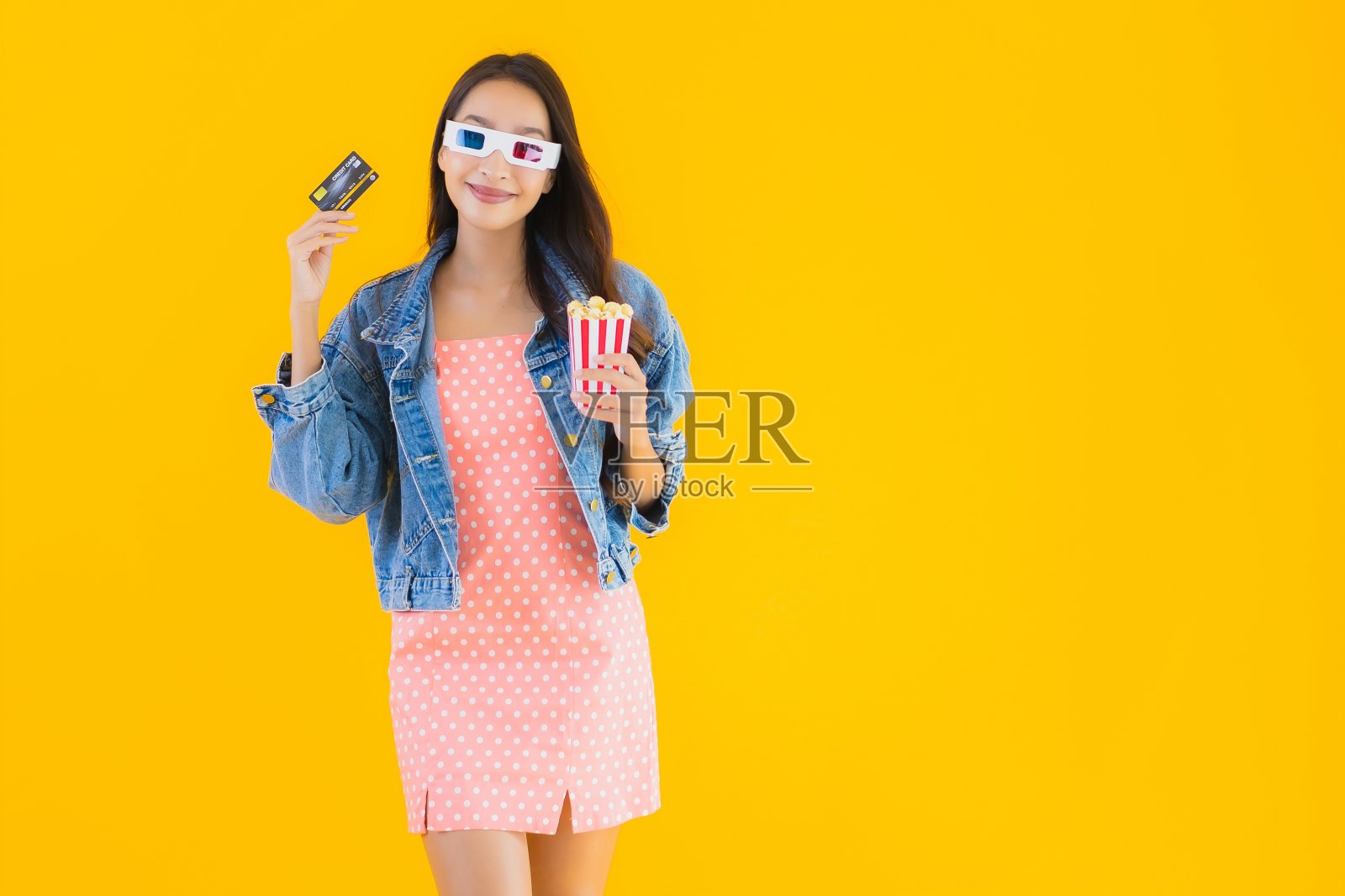 肖像美丽的年轻亚洲女人准备看电影与爆米花和信用卡照片摄影图片