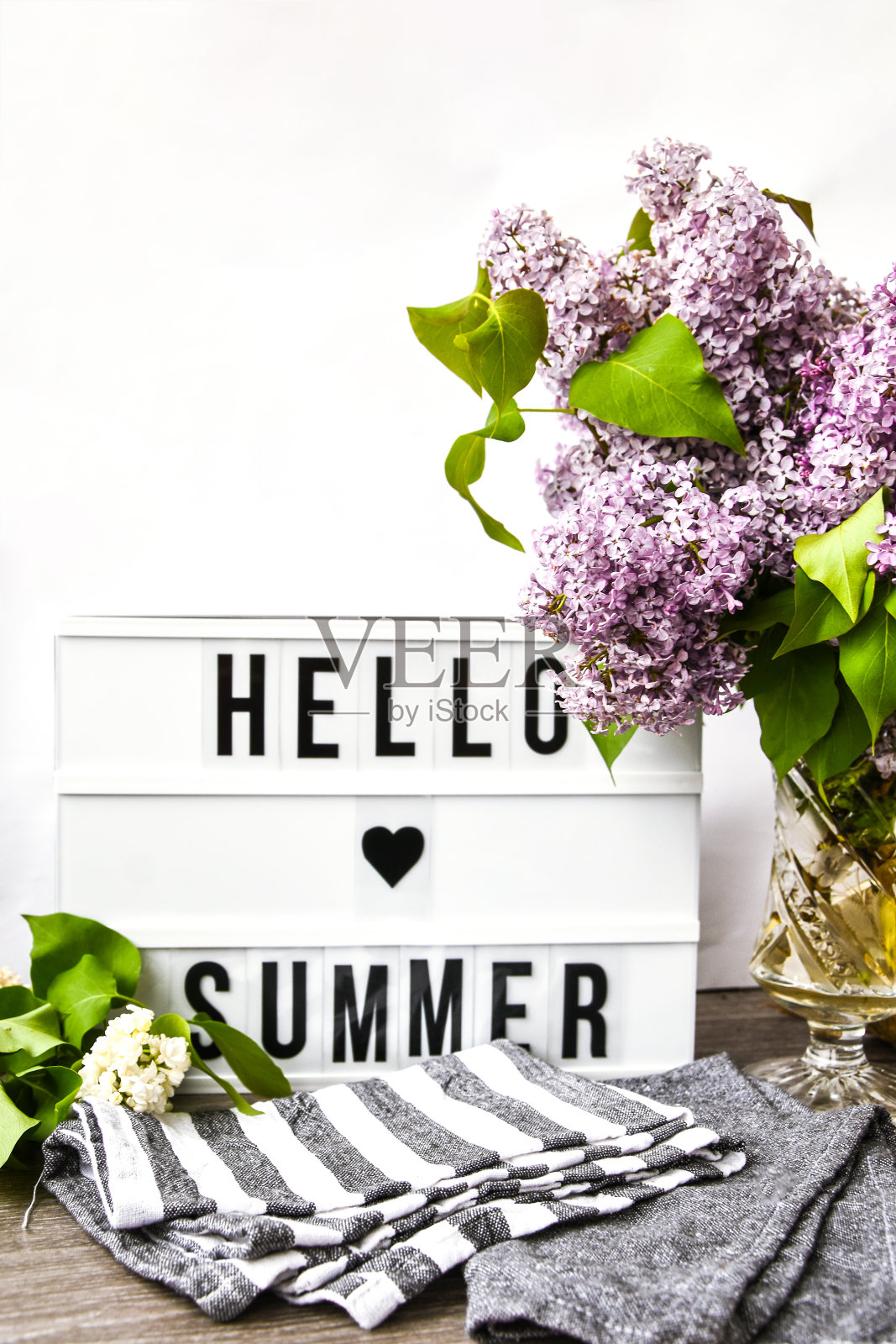 灯箱文字早安和一束紫丁香花在玻璃花瓶，春天的时间，书和绳子照片摄影图片